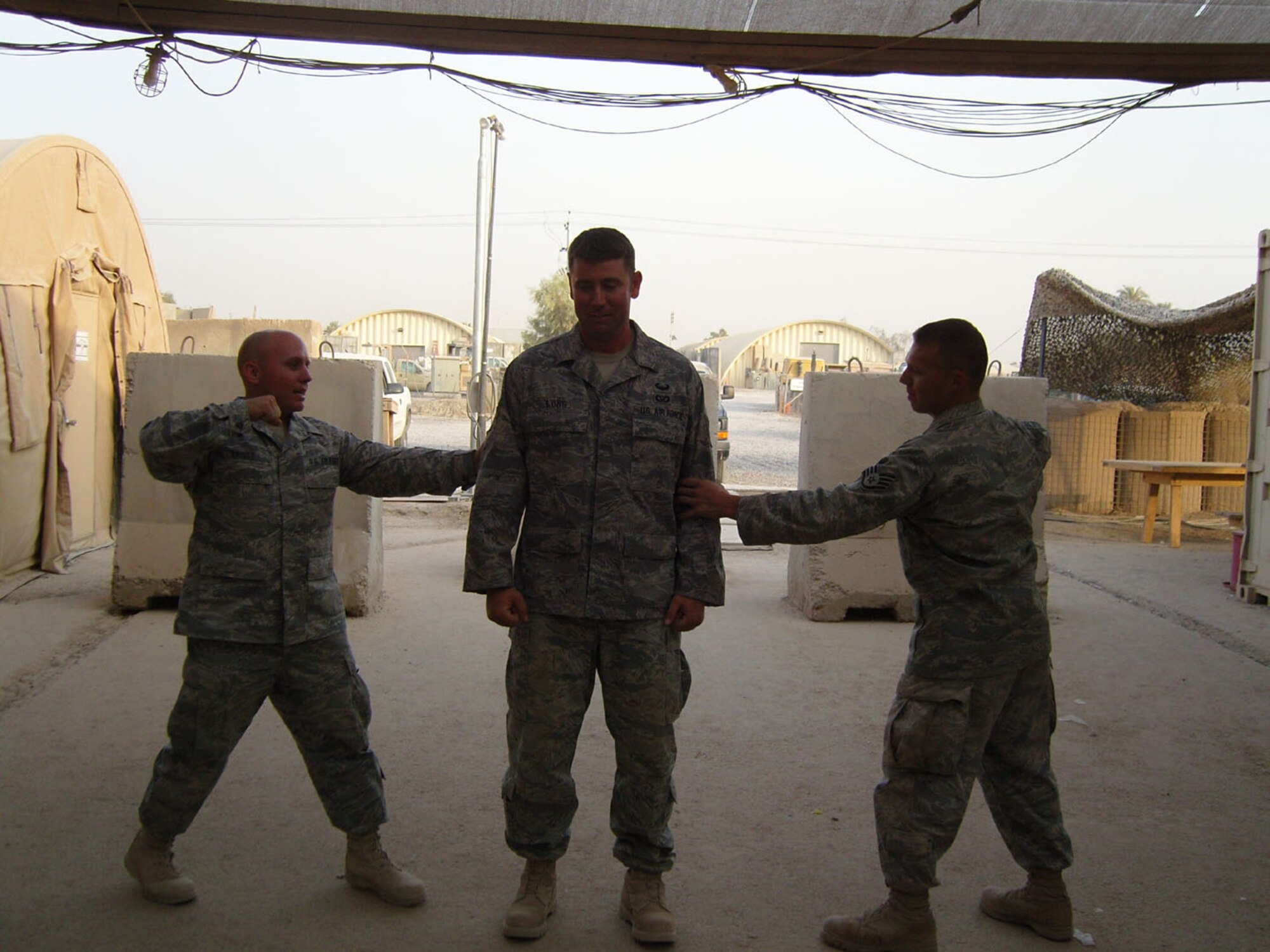 SEYMOUR JOHNSON AIR FORCE BASE, N.C. -- Staff Sgt. John Long (center), a Reservist with the 916th Civil Engineer Squadron, receives his new stripes while stationed at Balad International Airport, Iraq. Sgt. Long is a heavy equipment operator.