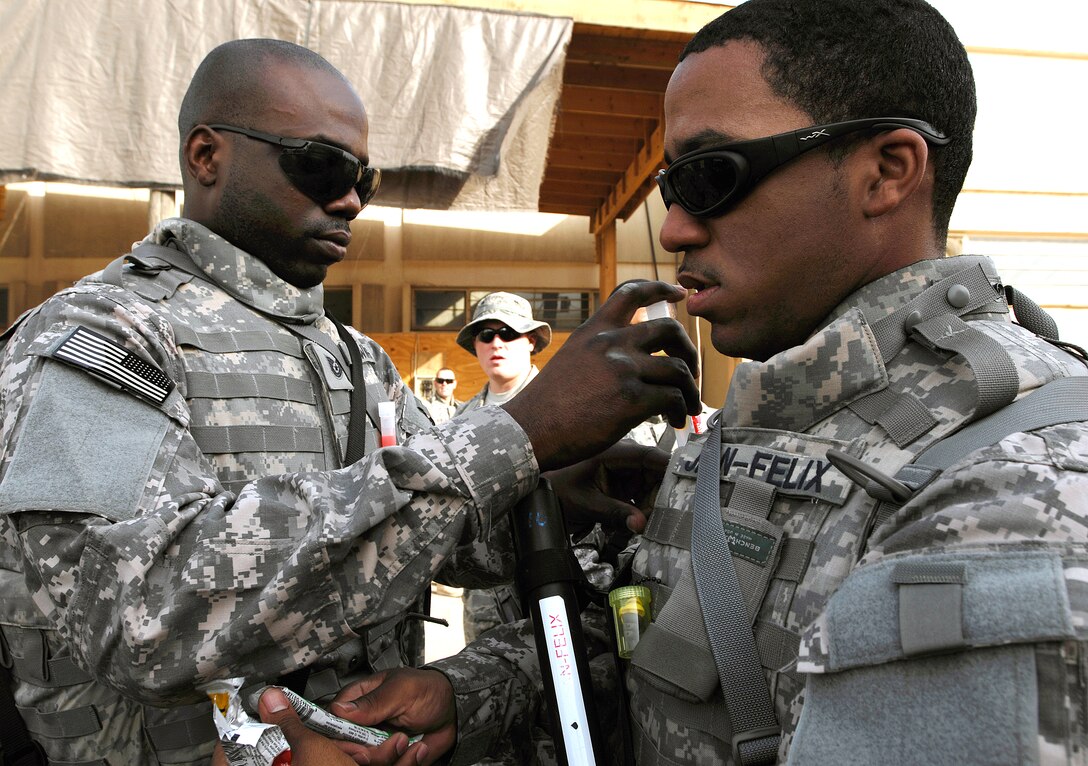 U.S. Air Force Tech. Sgt. Christopher Downing, left, inserts glow sticks into Staff Sgt. Jean Jean-Felix's body armor before a convoy operation on Joint Base Balad, Iraq, Sept. 4, 2008. Downing, a structural craftsman, and Jean-Felix, an electrical journeyman, are assigned to the 732nd Expeditionary Civil Engineer Squadron Utilities Detachment 6.