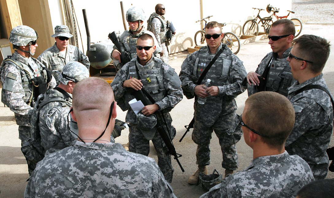 U.S. Air Force airmen gather around for a mission briefing before convoying outside the wire to a forward operating Joint Base Balad, Iraq, Sept. 4, 2008. The airmen are assigned to the 732nd Expeditionary Civil Engineer Squadron Utilities Detachment 6. The pre-mission safety and procedures briefing and pre-combat checks performed by team NCOs and officers are critical to personnel safety and mission success.