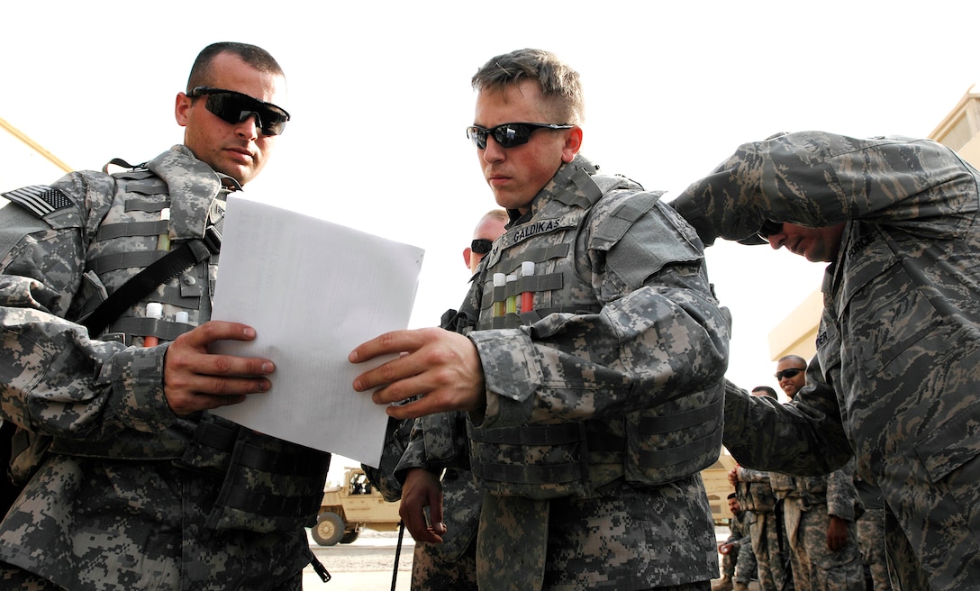 U.S. Air Force Staff Sgt. Joseph Webb, left, and Senior Airman Jeffrey Galdikas, middle, verify information while Senior Master Sgt. Garry Souder, right, adjusts Galdikas' body armor on Joint Base Balad, Iraq, Sept. 4, 2008. Webb, Galdikas and Souder are assigned to the 732nd Expeditionary Civil Engineer Squadron Utilities Detachment 6. 