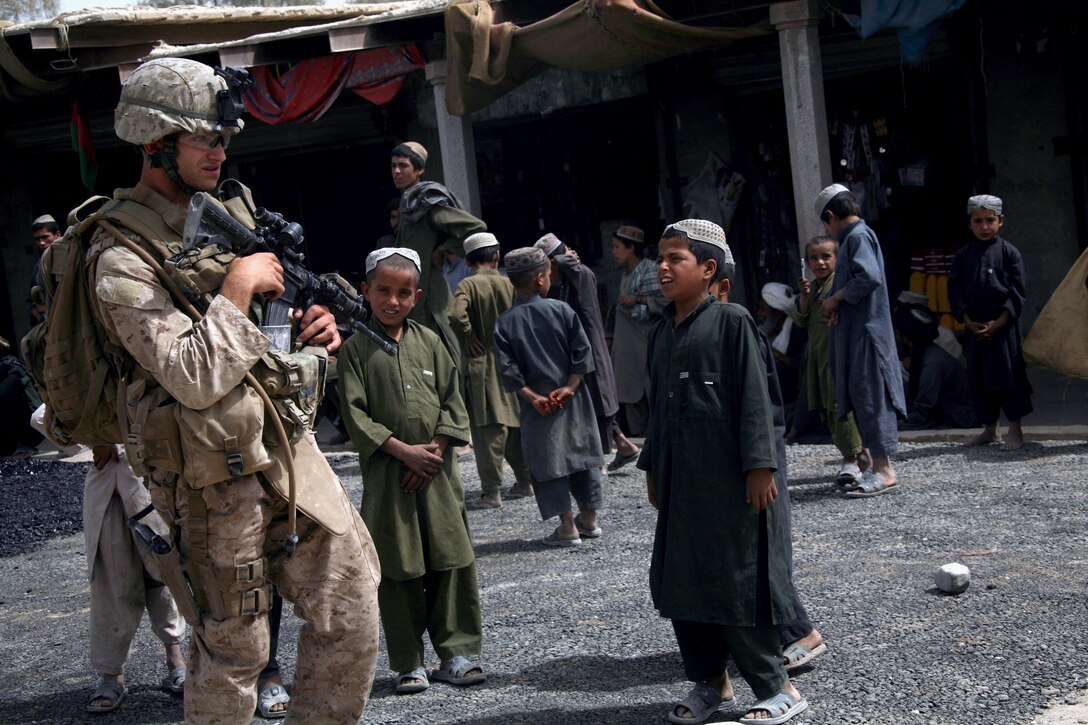 1st Lt. James C. McKendree, 2nd Platoon commander, Company E, TF 2/7, and Pearland, Texas native, is surrounded by local children during a patrol through the Sangin bazaar, Oct. 8.