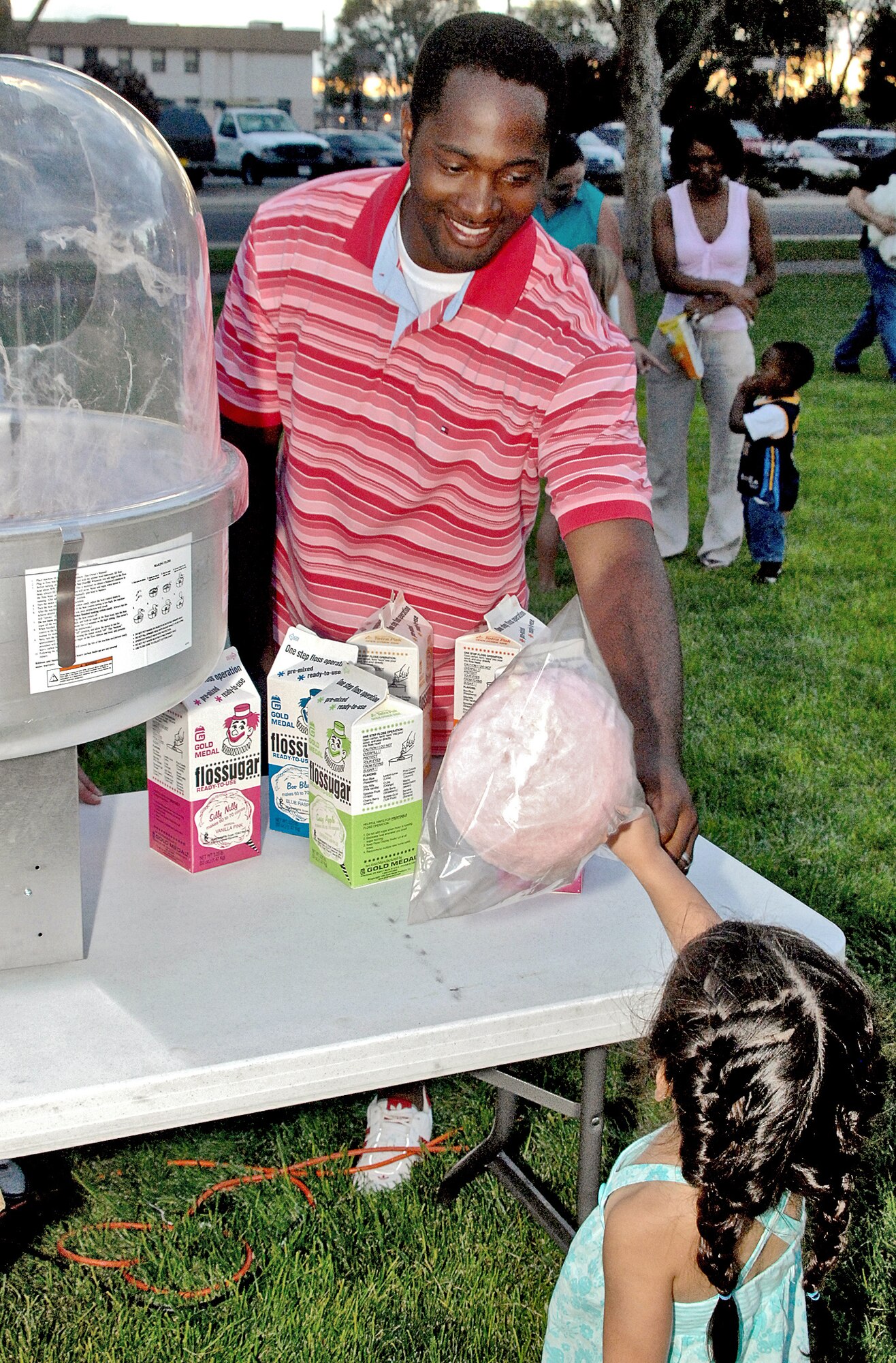Senior Airman Kenderric J. Callens, a Movie Under the Stars volunteer from the 898th Munitions Squadron, hands out free cotton candy to a movie goer. U.S. Air Force photo by Damian Bohannon