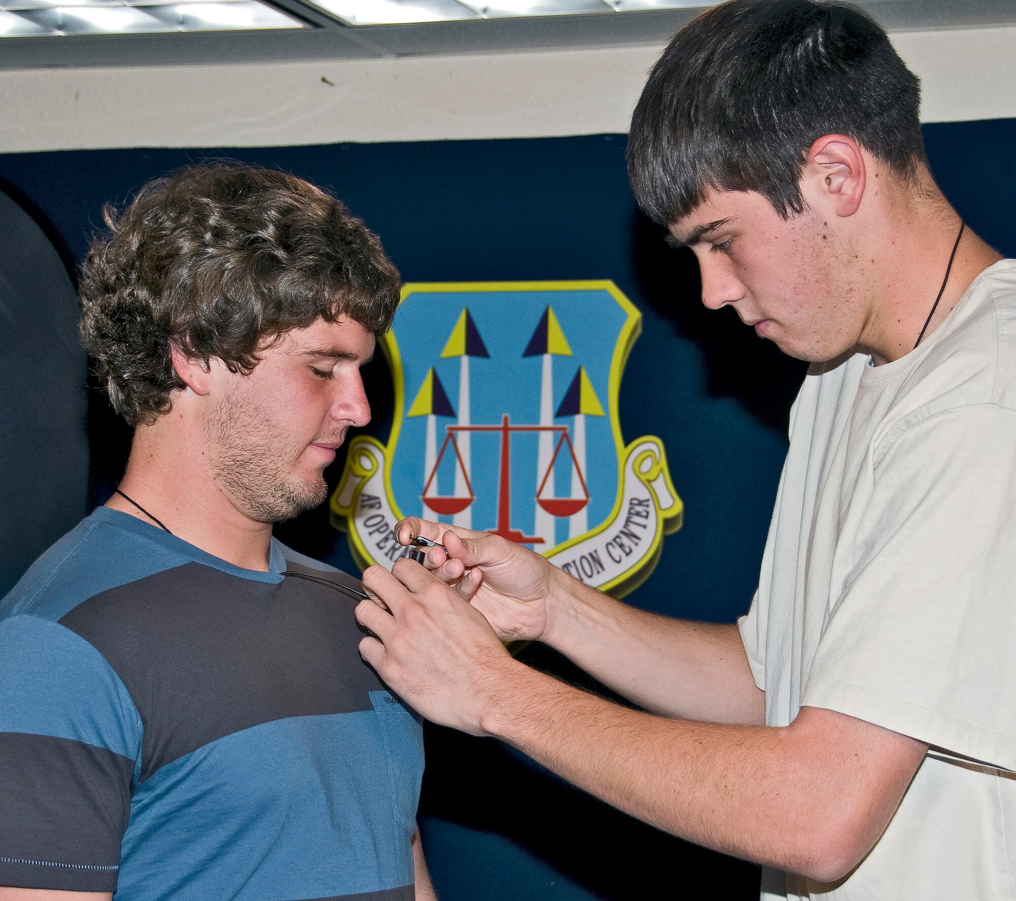 Calum Murray, left, a student intern with the Air Force Operational Test and Evaluation Center, waits as Ethan Halliday, another AFOTEC student intern, attaches a microphone in preparation for an interview. Both students are part of the AFOTEC program that exposes selected University of New Mexico students to the Air Force and to government service. Courtesy photo