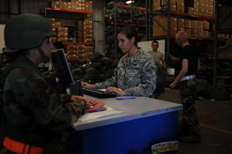 DYESS AIR FORCE BASE, Texas - Airman First Class Anna Jordan, 7th Logistics Readiness Squadron, issues cold weather bags and chemical warfare bags to airmen processing through the deployment line during the Operation Readiness Exercise at the Deployment Control Center, here, Sept. 6.  After issue, bags are divided into two piles based on their content. Exercises are designed to help Dyess AFB Airmen plan and prepare for real world deployments in support of war efforts. (U.S. Air Force photo/ Senior Airman Courtney Richardson)