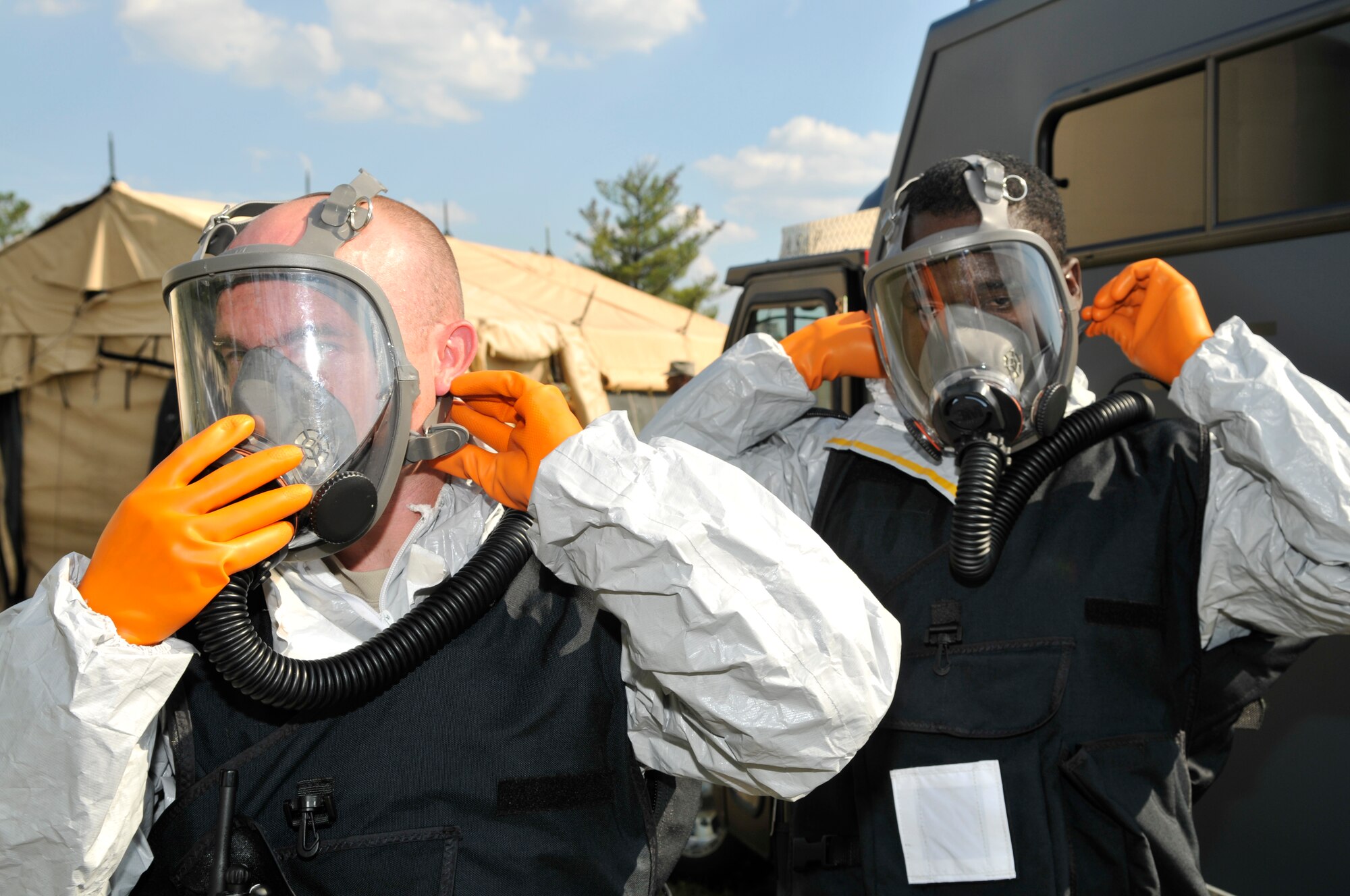 Airman 1st Class Jeffrey Collins and Staff Sgt. Beniteau Fenelus, both from the 305th Civil Engineer Squadron emergency management flight, put on their Level C Tyvec suits for hazardous material response before entering a tent containing a “suspicious” substance during a mobility exercise here Sept. 8. The “substance” turned out to be creamer from a supermarket. The suspicious substance was one of the scenarios used in the exercise to help prepare McGuire personnel for the upcoming Operational Readiness Inspection. (U.S. Air Force photo/Kenn Mann) 