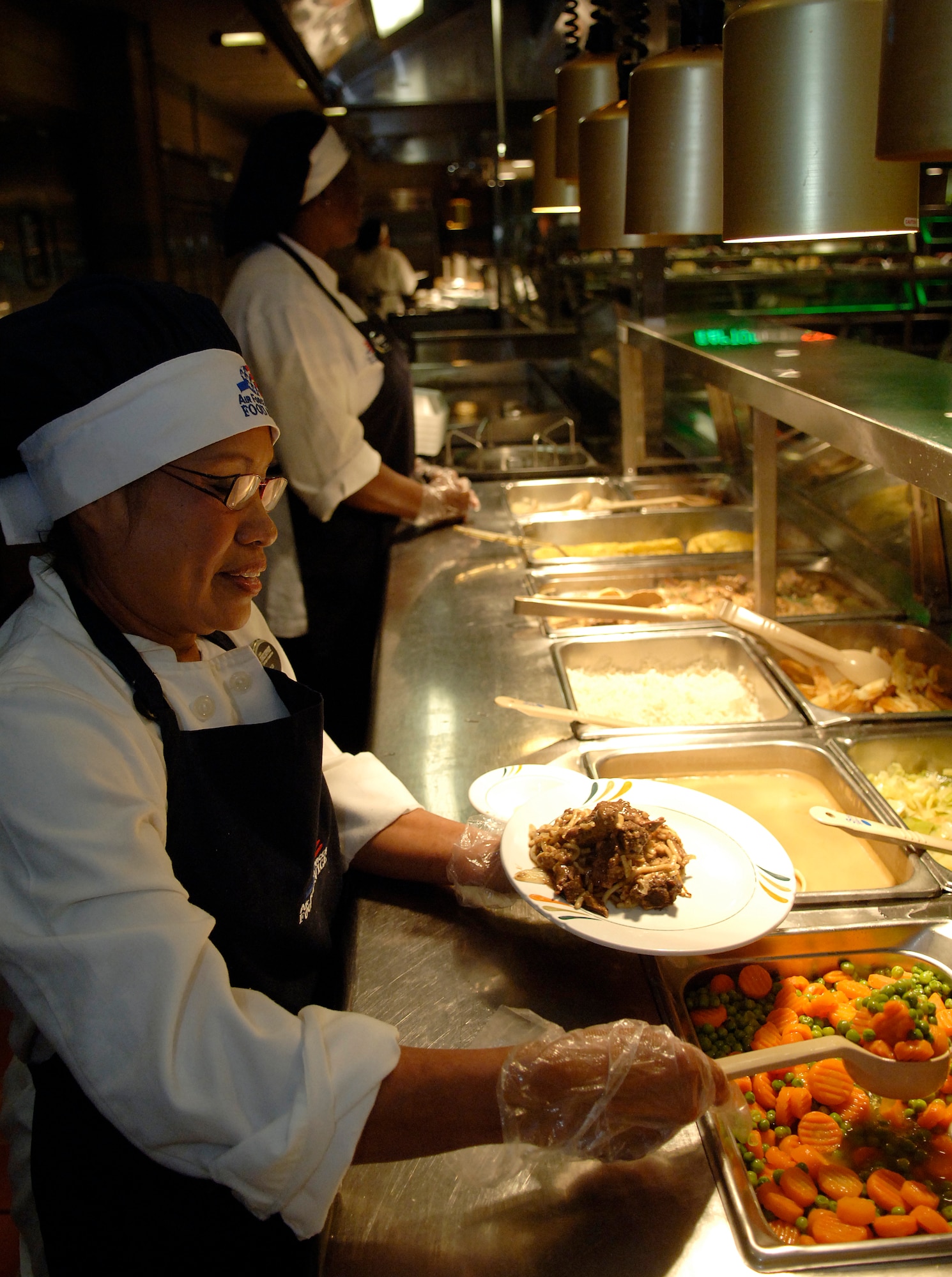 Ms. Chaluai Miles, 1st Force Support Squadron food service workers, serve lunch at the Eagle Room Dining Facility here on Aug. 27. (U.S. Air Force photo/Tech. Sgt. Levi Collins) 