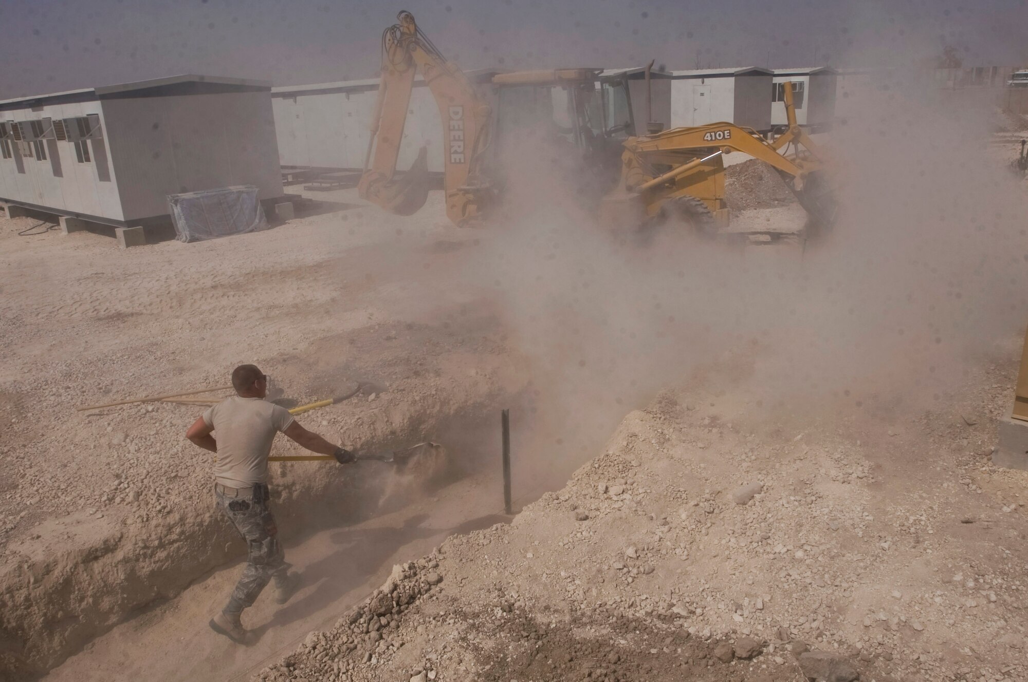 At Ali Base, Iraq, Staff Sgt. Trevor Petersma levels sand as it is poured into a trench Aug. 15.  The 407th Expeditionary Civil Engineer Squadron is rerouting the power supply, and laying water and sewage systems in the transition from base tents to trailers. Sergeant Petersma is a utilities systems craftsman with the 407th ECES. (U.S. Air Force photo/Airman 1st Class Christopher Griffin) 