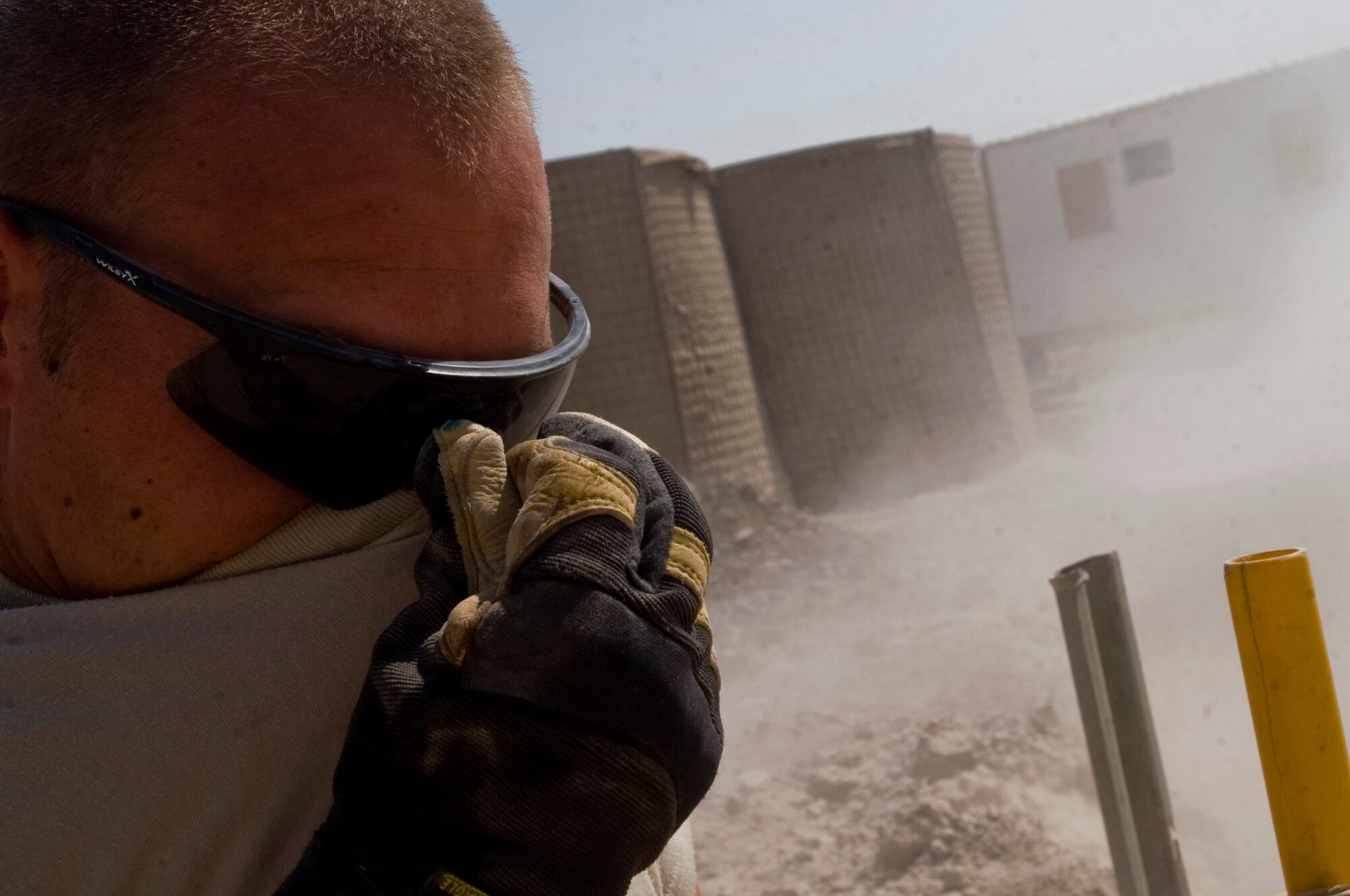 Staff Sgt. Trevor Petersma protects his face from sand as it is poured into a trench Aug. 15 at Ali Base, Iraq. In the transition from tents to trailers, the 407th Expeditionary Civil Engineer Squadron is rerouting the power supply and laying water and sewage systems. Sergeant Petersma, a utilities systems craftsman with the 407th ECES, is deployed from Malmstrom Air Force Base, Mont. (U.S. Air Force photo/Airman 1st Class Christopher Griffin) 
