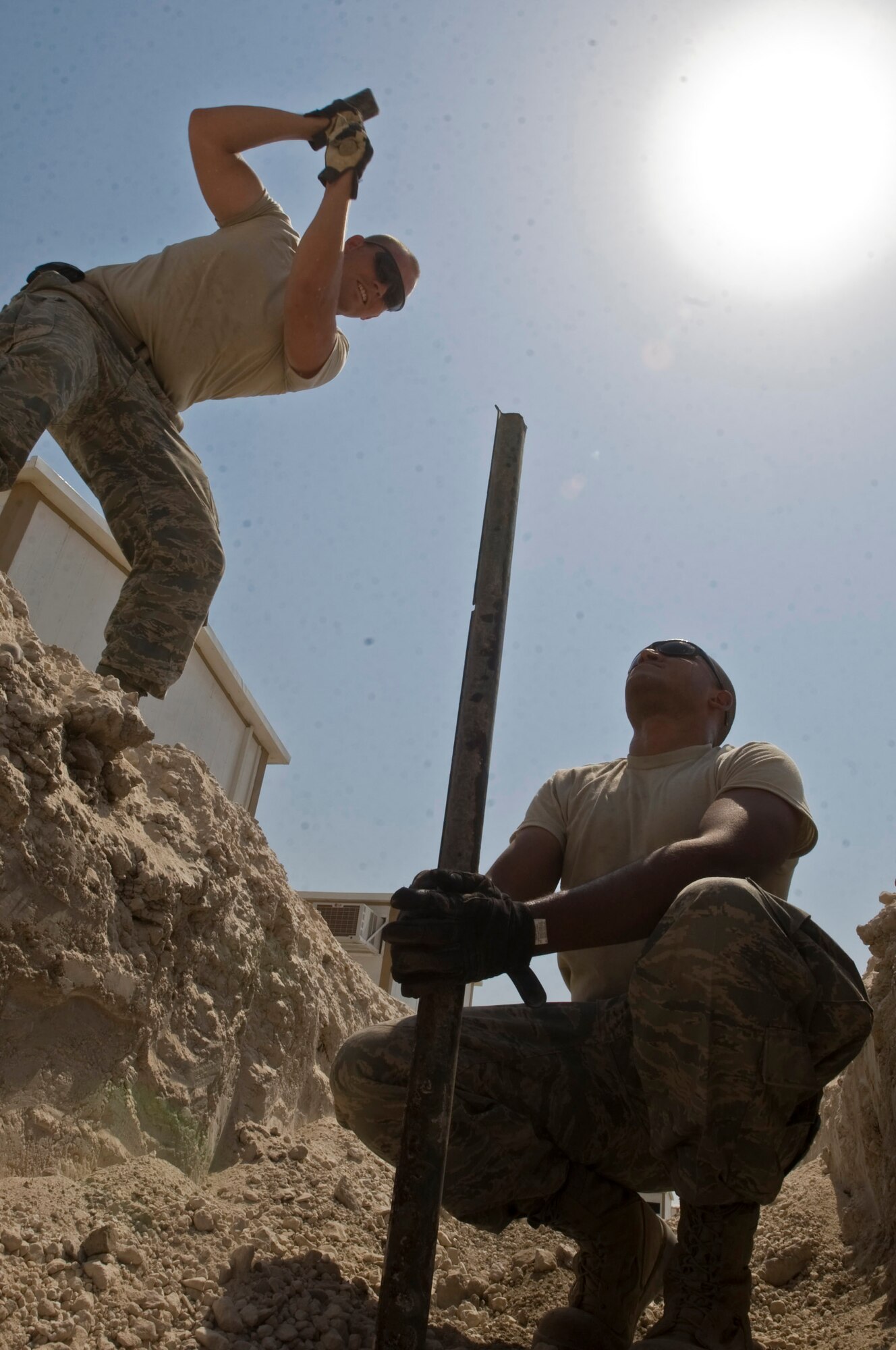 Staff Sgt. Trevor Petersma and Airman 1st Class Aaron Weathers measure the distance between metal supports for water and sewage lines Aug. 15 at Ali Base, Iraq. In the transition from base tents to trailers, the 407th Expeditionary Civil Engineer Squadron is rerouting the power supply along with laying water and sewage systems. Sergeant Petersma is deployed from Malmstrom Air Force Base, Mont., and Airman Weathers is deployed from F.E. Warren AFB, Wyo. (U.S. Air Force photo/Airman 1st Class Christopher Griffin) 
