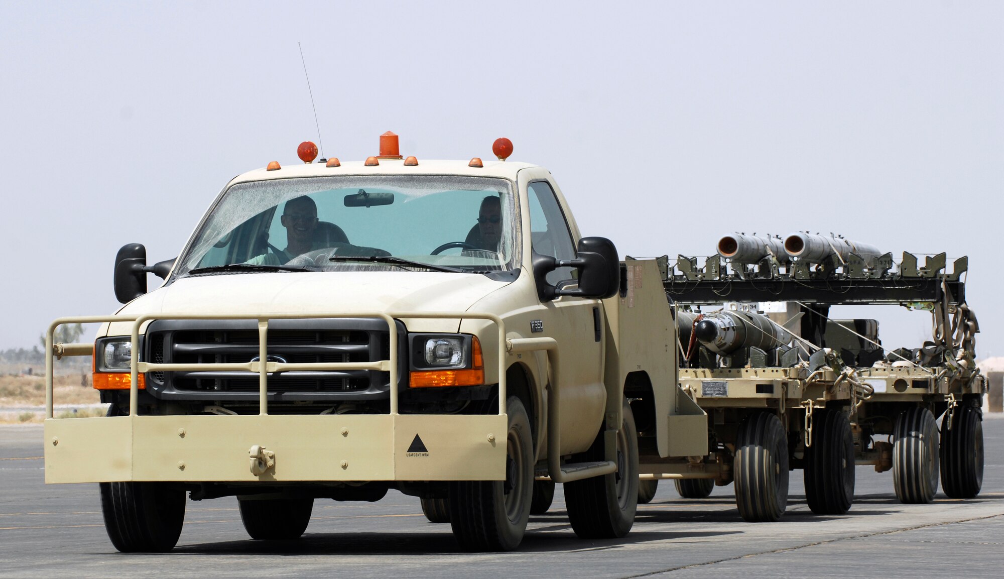 JOINT BASE BALAD, Iraq -- Airmen from the 332nd Expeditionary Maintenance Squadron tow bombs down a taxiway here Sept. 2. After the munitions are built, they are transported to a secure area for storage until needed. Joint Base Balad aircraft that use these munitions include F-16 Fighting Falcons and MQ-1 Predator and MQ-9 Reaper unmanned aerial systems. (U.S. Air Force photo/Airman 1st Class Jason Epley)
