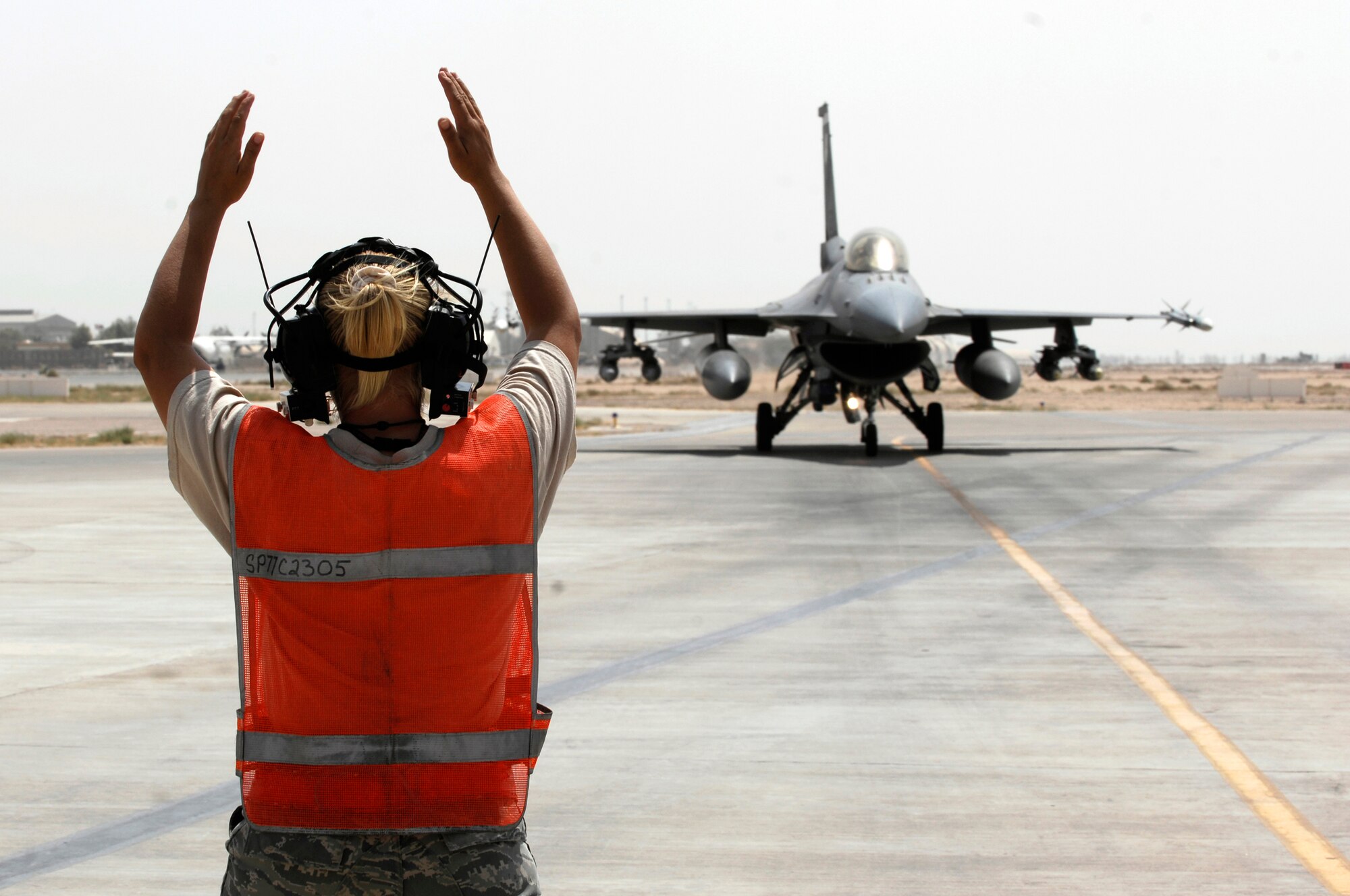 JOINT BASE BALAD, Iraq -- Senior Airman Samantha Bashaw marshals an F-16 Fighting Falcon onto a de-arming ramp here Sept. 2. Aircraft must be de-armed after flying combat sorties. Bashaw, a weapons load crewmember assigned to the 77th Expeditionary Fighter Squadron here, is deployed from Shaw Air Force Base, S.C. Her hometown is Hayfork, Calif. (U.S. Air Force photo/Airman 1st Class Jason Epley)