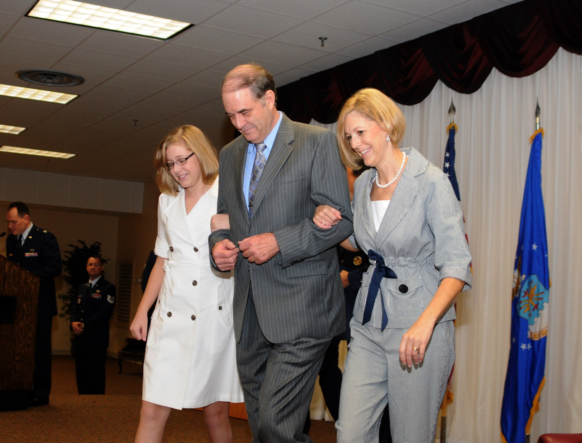 Master Sgt. (Ret) Terry Aycode, a former squadron mate of General Touhill, escorts Charlene and Kate Touhill from the stage during the promotion ceremony (U.S. Air Force photo by Kemberly Groue).