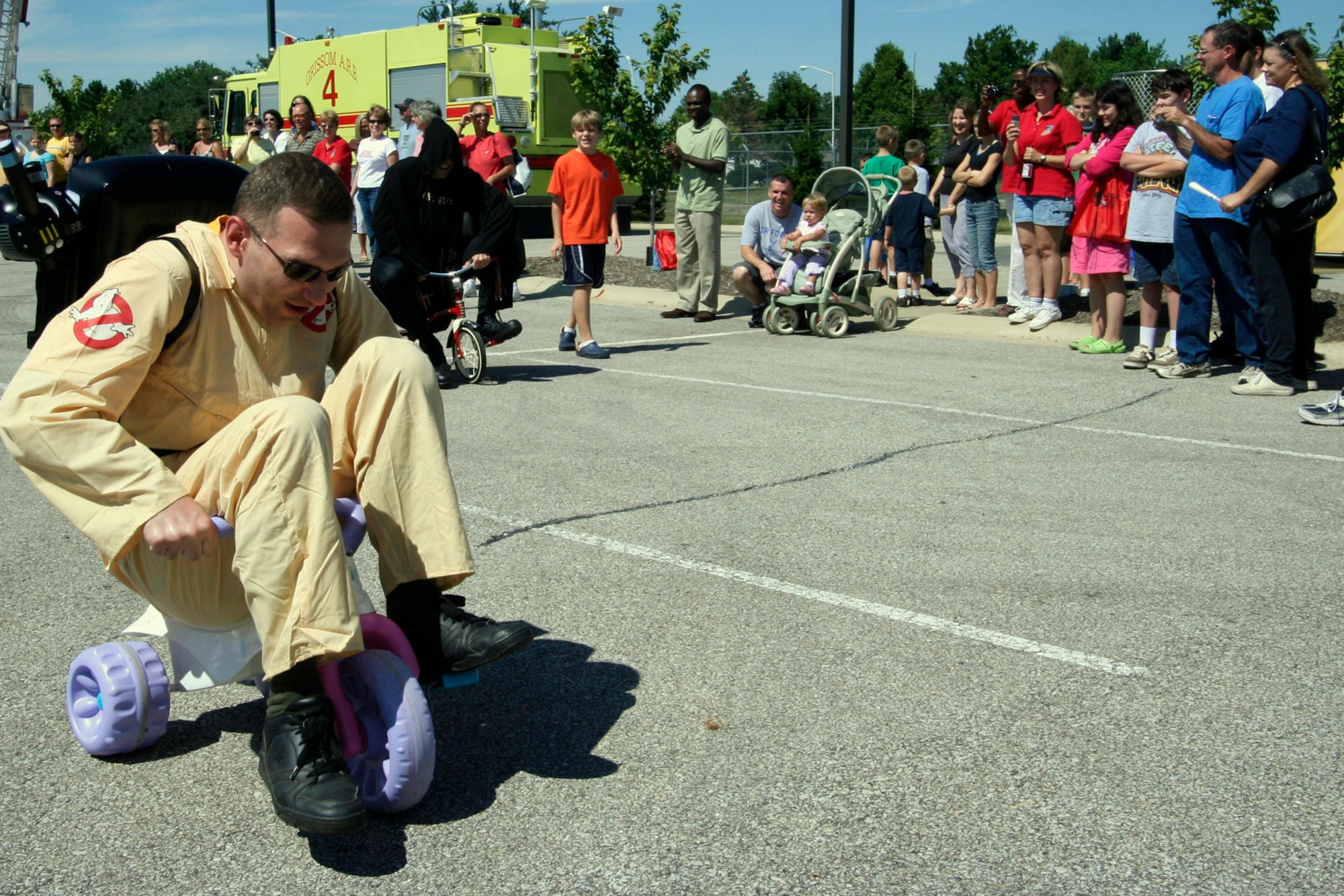 GRISSOM AIR RESERVE BASE, Ind., -- Maj. Michael Polomchak, 434th Maintenance Operations Flight commander, employs a unique over the handle-bar peddling style during the commander's tricycle race. The major was dressed as a Ghost Buster for the event. (U.S. Air Force photo/Tech. Sgt. Patrick Kuminecz)