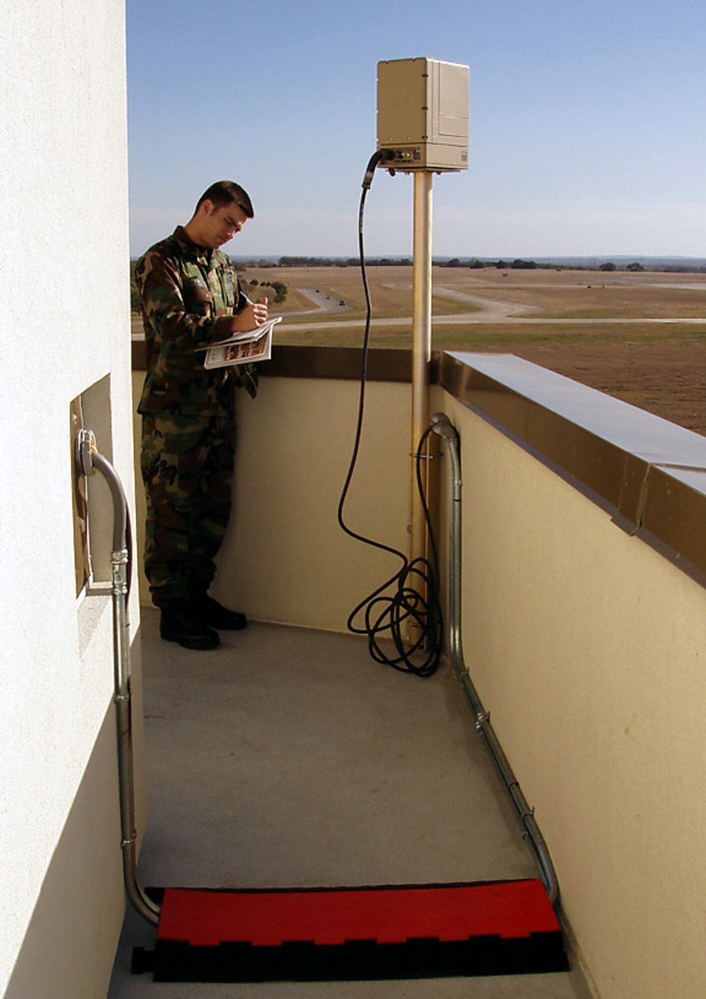 Capt. Max Gulezian inspects a wide-area surveillance thermal imager as part of the Transformational Technology Insertion equipment suite now installed on the airfield tower balcony at Randolph Air Force Base, Texas. The imager provides color and thermal image surveillance capability that is relayed back to a base's law enforcement desk. Captain Gulezian is a 642nd Electronic Systems Squadron Transformational Technology Insertion program manager. (Courtesy photo) 