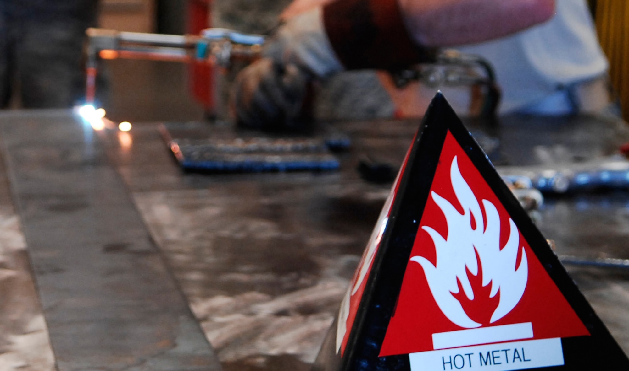 CANNON AIR FORCE BASE, N.M. - A warning sign shows the seriousness of the oxy-acetylene torch being used in the background. The new torch was demonstrated to wing leadership Sept. 5 by the 27th Special Operations Equipment Maintenance Squadron's Fabrications Flight. (U.S. Air Force photo/Airman 1st Class Evelyn Chavez)