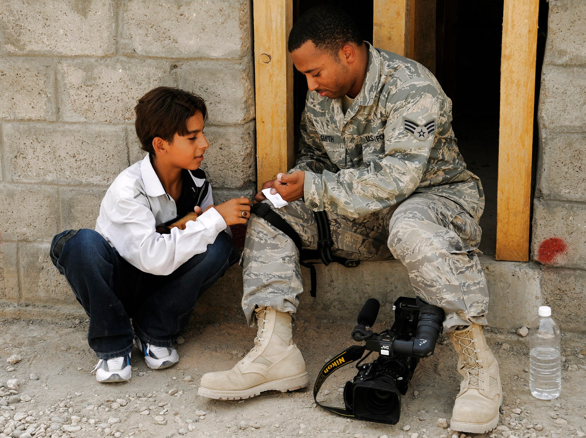 Senior Airman Robert Smith shows an Iraqi boy how to write his name in English at Hawr Rajab, Iraq, Aug. 28. Airman Smith is a broadcaster with U.S. Air Forces Central -- Baghdad Media Outreach Team. (U.S. Air Force photo/Staff Sgt. Paul Villanueva II)