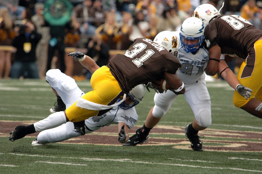 U.S. Air Force Academy strong safety Chris Thomas and defensive end Ryan Kemp combine to bring down Wyoming running back Wynel Seldon Sept. 6 in Laramie, Wyo. The Falcons defense held Wyoming to 140 yards rushing and limited Seldon to 67 yards on 10 carries in the Falcons' 23-3 win over Wyoming. (U.S. Air Force photo/John Van Winkle) 