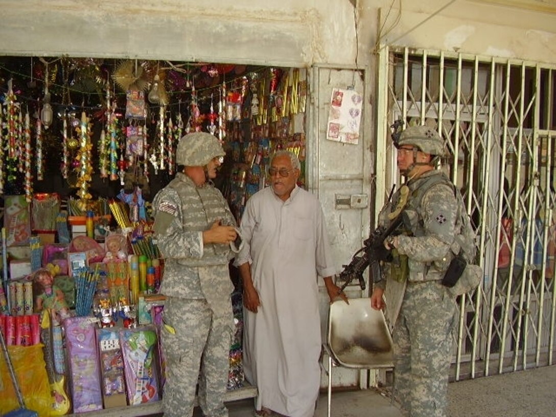 Army 1st Lt. Matthew George, a Los Angeles native, talks with a candle shop owner in northern Baghdad’s Shaab neighborhood with the help of an interpreter during a patrol, Sept. 6, 2008. U.S. Army photo by 1st Lt. Dan Rullo, Multinational Division Baghdad