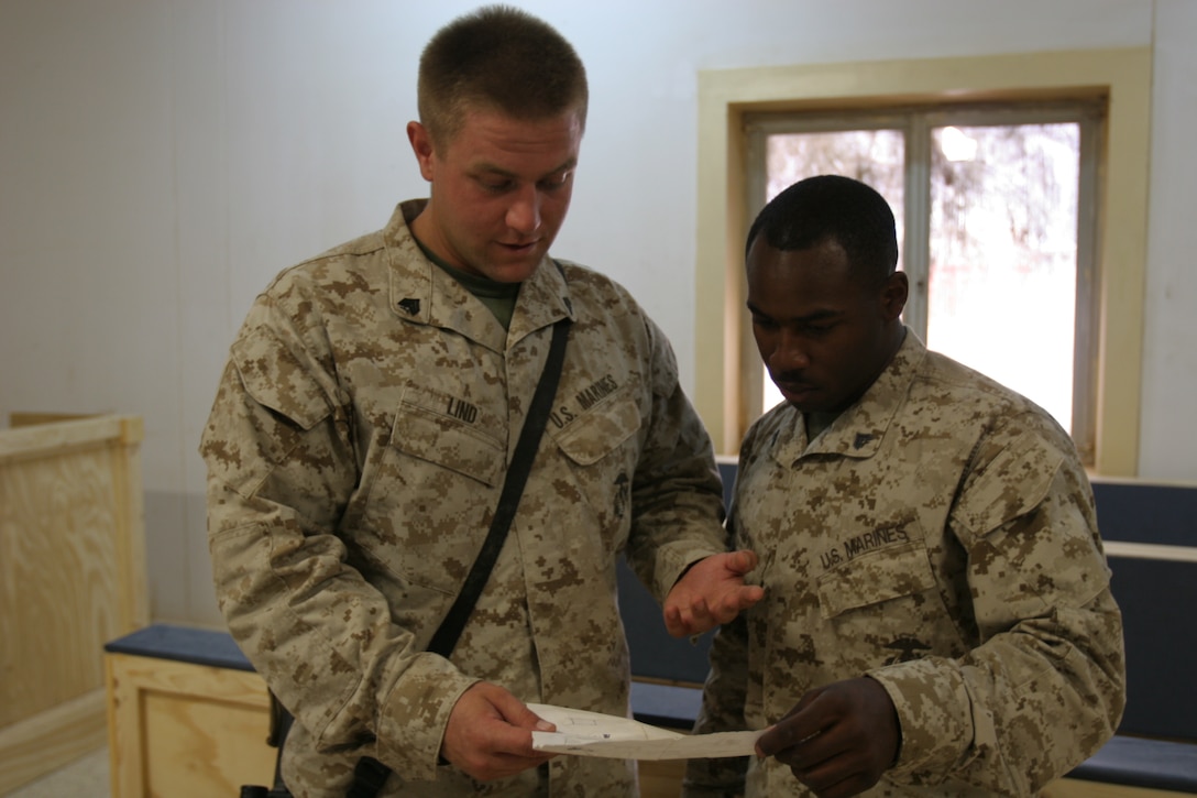 Cpl. John Turpin (right), combat engineer with Marine Wing Support Squadron 172, Marine Wing Support Group 37, 3rd Marine Aircraft Wing (Forward) reviews the schematics of the courtroom project with fellow combat engineer, Sgt. Gabriel Linn Sept. 9. Turpin credits Linn for helping him find design ideas and materials for the project.