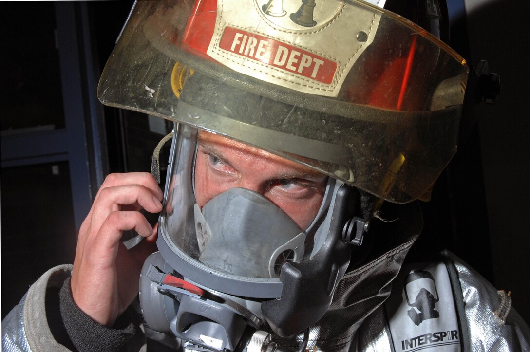 Staff Sgt. Jason Utt, 28th Civil Engineer Squadron crew chief fire fighter, adjusts his gas mask during a anti-terrorism exercise Sept. 10. The 28 CES fire fighters responded to the simulated explosion and conducted thorough inspections in the Rushmore Inn dormitory. (U.S. Air Force photo by Airman Corey Hook)
