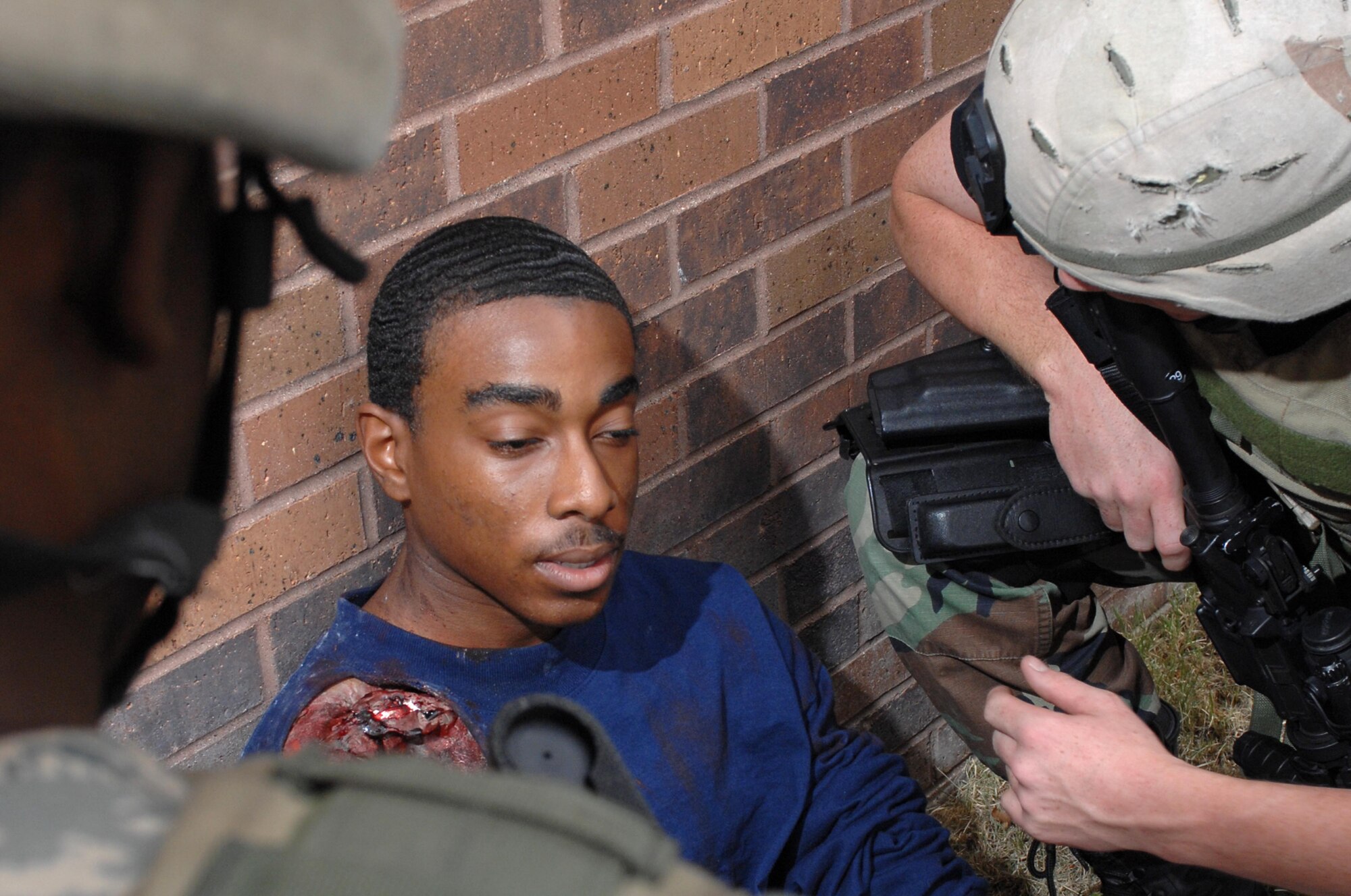 (Left) Senior Airman Steven Oliver and Airman 1st Class Jeff Gordon, 28th Security Forces military police officers, aid exercise role-player Airman Bryan Ambrose, 28th Operations Support Squadron intel analyst, during an anti-terrorism exercise Sept. 10. Airman Bryan Ambrose acted as if he had severe shock from the simulated explosion. (U.S. Air Force photo by Airman Corey Hook)