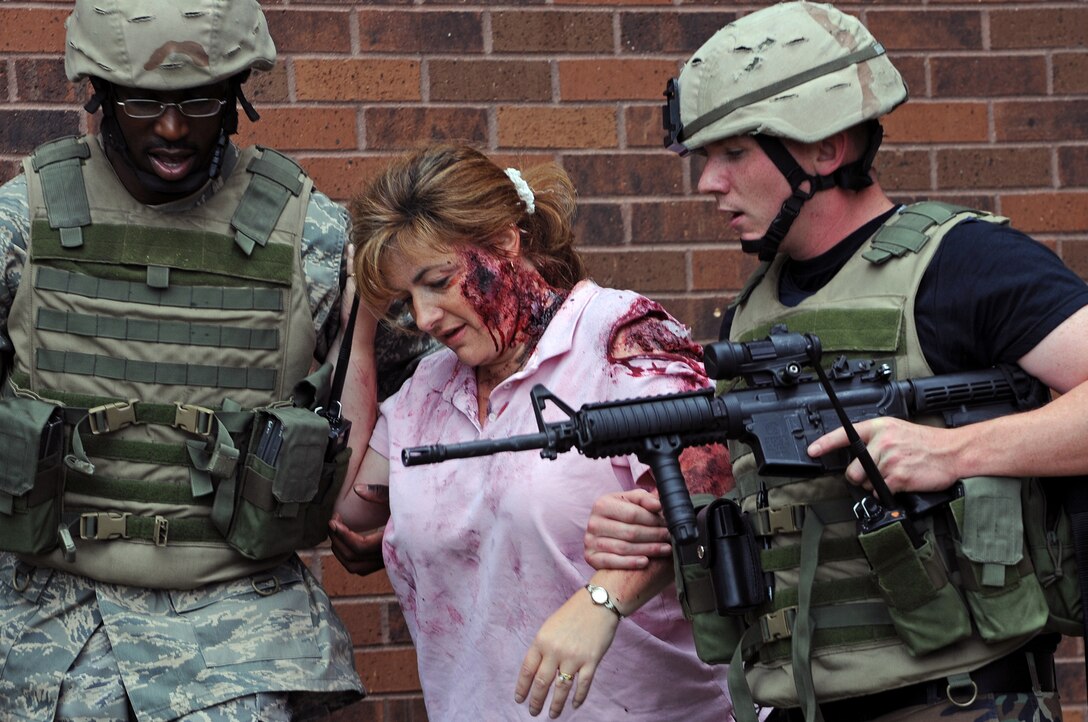 (Left) Senior Airman Steven Oliver and Airman 1st Class Jeffrey Gordon, 28th Security Forces Squadron police officers, help transport Karen Howe, exercise role player, to safety during an anti-terrorism force protection exercise on Sept. 10. Airman Oliver and Airman Gordon assisted ten people with medical care and evacuation from dangerous areas. (U.S. Air Force photo/Senior Airman Marc I. Lane)