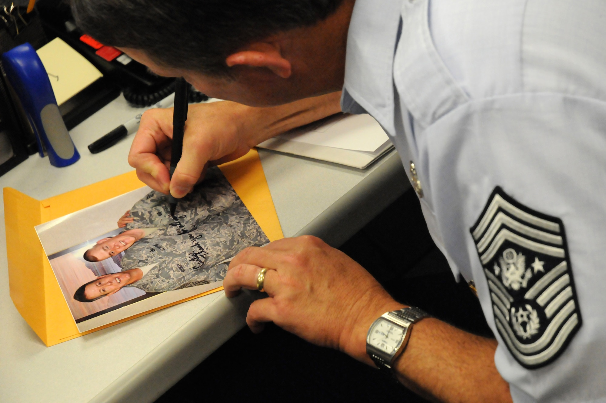 Chief Master Sgt. of the Air Force Rodney J. McKinley takes time to sign a photo for Senior Airman Curtis Morrison during his visit to the National Air and Space Intelligence Center Sept. 8 at Wright-Patterson Air Force Base, Ohio. During his visit, the chief visited with enlisted, officer and civilian employees and answered questions from Airmen. He is the 15th chief master sergeant of the Air Force. (U.S. Air Force photo/Staff Sgt. Joshua Strang) 
