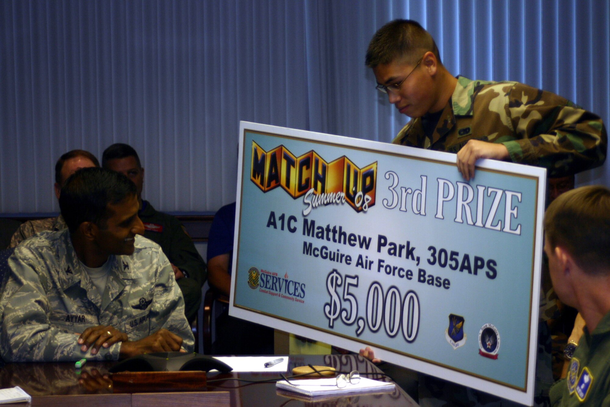 Right, Airman 1st Class Matthew Park, 305th Aerial Port Squadron, won the Air Mobility Command MatchUp 2008 third place prize – a check for $5000. Col. Balan Ayyar, 305th Air Mobility Wing commander, along with Col. Benjamin Trotter, AMC Services commander (via a conference call), and the 305th Services Squadron marketing team surprised Airman Park with the check during a wing stand-up meeting Sept. 10 here. Last year at McGuire, Master Sgt. David Warner won the AMC MatchUp 2007 grand prize -- a 2007 SAAB Aero 9-3. (U.S. Air Force photo/Airman 1st Class Bekah Phy)