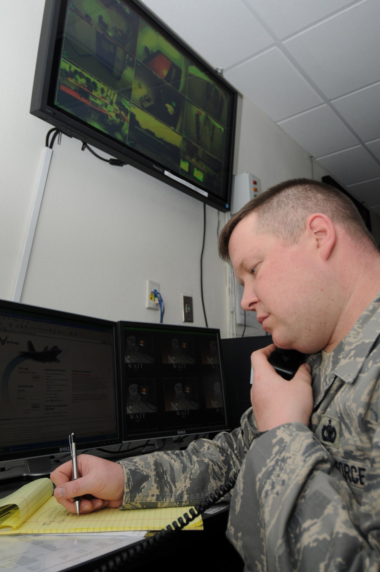 Staff Sgt. Michael Hall takes a phone call inside the base defense operations center.  He keeps an eye on surveillance screens that show inbound and outbound traffic lanes and other locations.  (U.S. Air Force photo by Kemberly Groue)