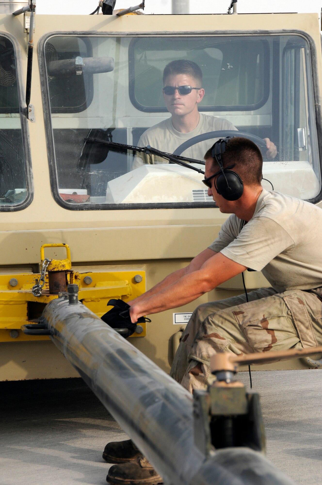 Airman 1st Class Brian Decker tugs on the tow bar lining up the tow bar and a tow vehicle operated by Staff Sgt Jon Mirro Sept. 9, 2008.  .  The directions are necessary to achieve a proper connection between the tow vehicle and the B-1 Lancer.  The tow vehicle will be used to back the B-1 into a parking space on the ramp at this undisclosed air base in Southwest Asia. The B-1 is called upon daily to support ground forces engaged in both Operations Iraqi and Enduring Freedom.  It carries the largest payload of both guided and unguided weapons in the Air Force inventory and is the backbone of America's long-range bomber force. It can rapidly deliver massive quantities of precision and non-precision weapons against any adversary, anywhere in the world, at any time. Sergeant Mirro is a native of Ellensburg, Wash., and Airman Decker hails from Murphy, N.C. Both are assigned to the 379th Expeditionary Aircraft Maintenance Squadron, 34th Aircraft Maintenance Unit, and are deployed from Ellsworth Air Force Base, S.D. (U.S. Air Force photo by Tech. Sgt. Michael Boquette/Released)