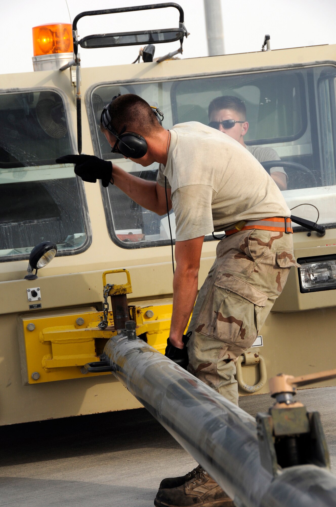 Airman 1st Class Brian Decker directs the approach of tow vehicle operator Staff Sgt. Jon Mirro Sept. 9, 2008.  The directions are necessary to achieve a proper connection between the tow vehicle and the B-1 Lancer.  The tow vehicle will be used to back the B-1 into a parking space on the ramp at this undisclosed air base in Southwest Asia. The B-1 is called upon daily to support ground forces engaged in both Operations Iraqi and Enduring Freedom.  It carries the largest payload of both guided and unguided weapons in the Air Force inventory and is the backbone of America's long-range bomber force. It can rapidly deliver massive quantities of precision and non-precision weapons against any adversary, anywhere in the world, at any time. Sergeant Mirro is a native of Ellensburg, Wash., and Airman Decker hails from Murphy, N.C. Both are assigned to the 379th Expeditionary Aircraft Maintenance Squadron, 34th Aircraft Maintenance Unit, and are deployed from Ellsworth Air Force Base, S.D.  (U.S. Air Force photo by Tech. Sgt. Michael Boquette/Released)