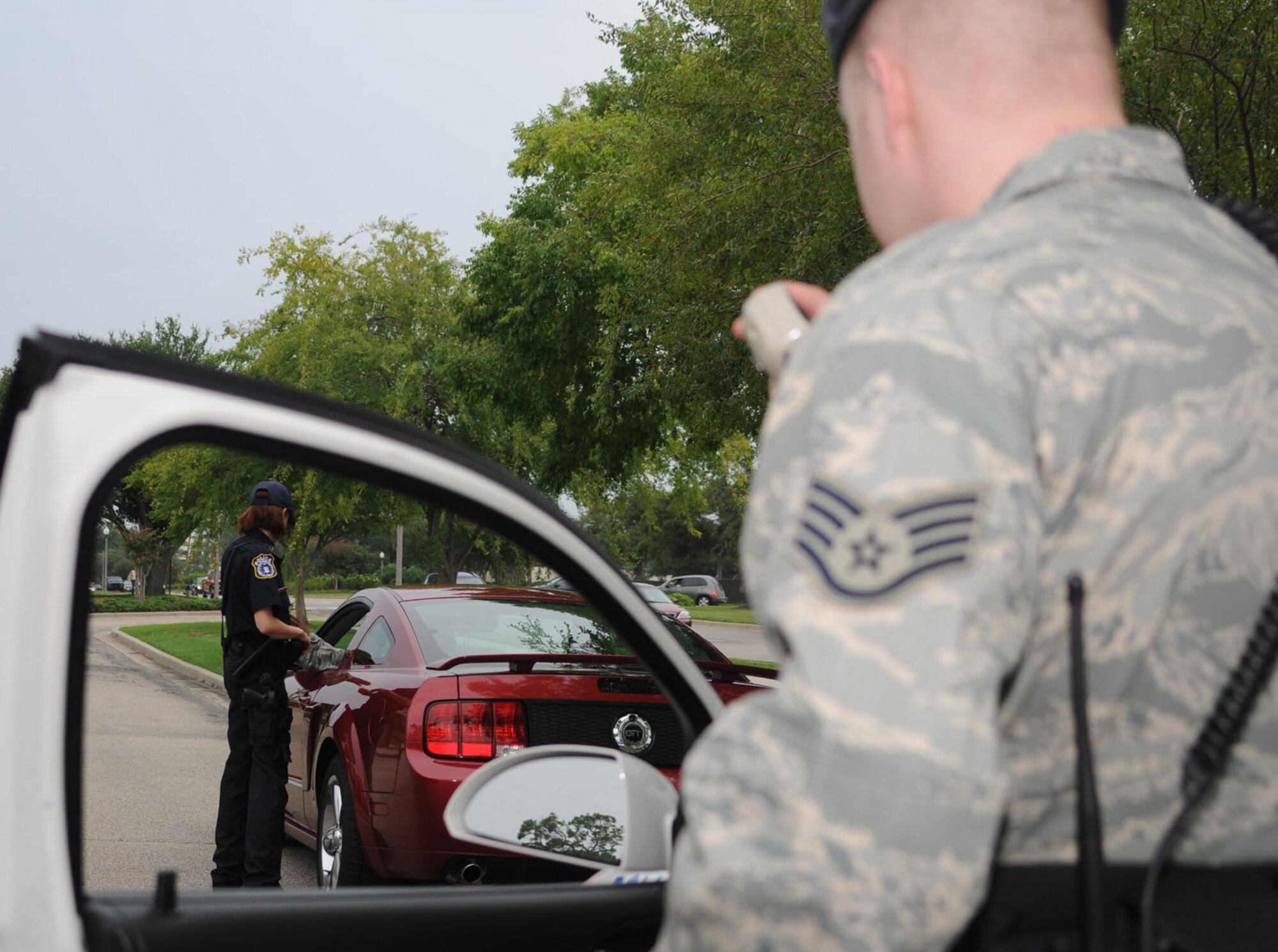 Teri Allbaugh, left, a civilian security forces member, checks a driver’s license during a traffic stop, while Staff Sgt. Brandon Harty calls in the stop.  (U.S. Air Force photo by Kemberly Groue)