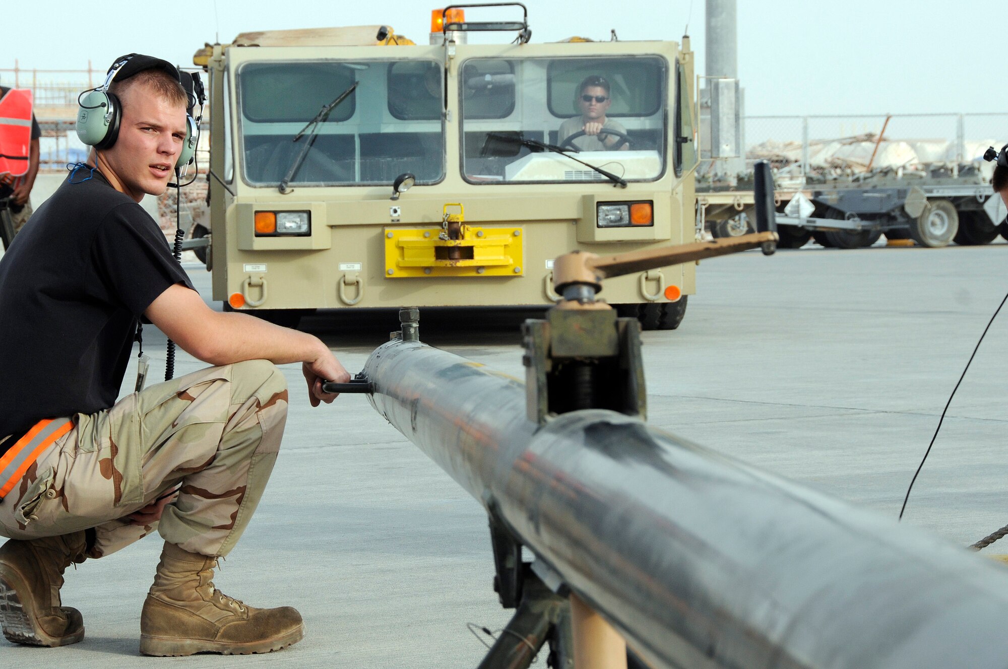 Senior Airman William Seaborne, 379th Expeditionary Aircraft Maintenance Squadron, 34th Aircraft Maintenance Unit, ensures everything is clear before waving a tow vehicle towards a B-1B Lancer and connecting the tow bar Sept. 9, 2008.  Staff Sgt. Jon Mirro, also from the 34th AMU, awaits signals before moving forward the tow vehicle and connecting.  The tow vehicle will be used to back the B-1 into a parking space on the ramp at this undisclosed air base in Southwest Asia. The B-1 is called upon daily to support ground forces engaged in both Operations Iraqi and Enduring Freedom.  It carries the largest payload of both guided and unguided weapons in the Air Force inventory and is the backbone of America's long-range bomber force. It can rapidly deliver massive quantities of precision and non-precision weapons against any adversary, anywhere in the world, at any time. Sergeant Mirro is a native of Ellensburg, Wash., and Airman Seaborne hails from Campbellsville, Ky. Both are deployed from Ellsworth Air Force Base, S.D. (U.S. Air Force photo by Tech. Sgt. Michael Boquette/Released)