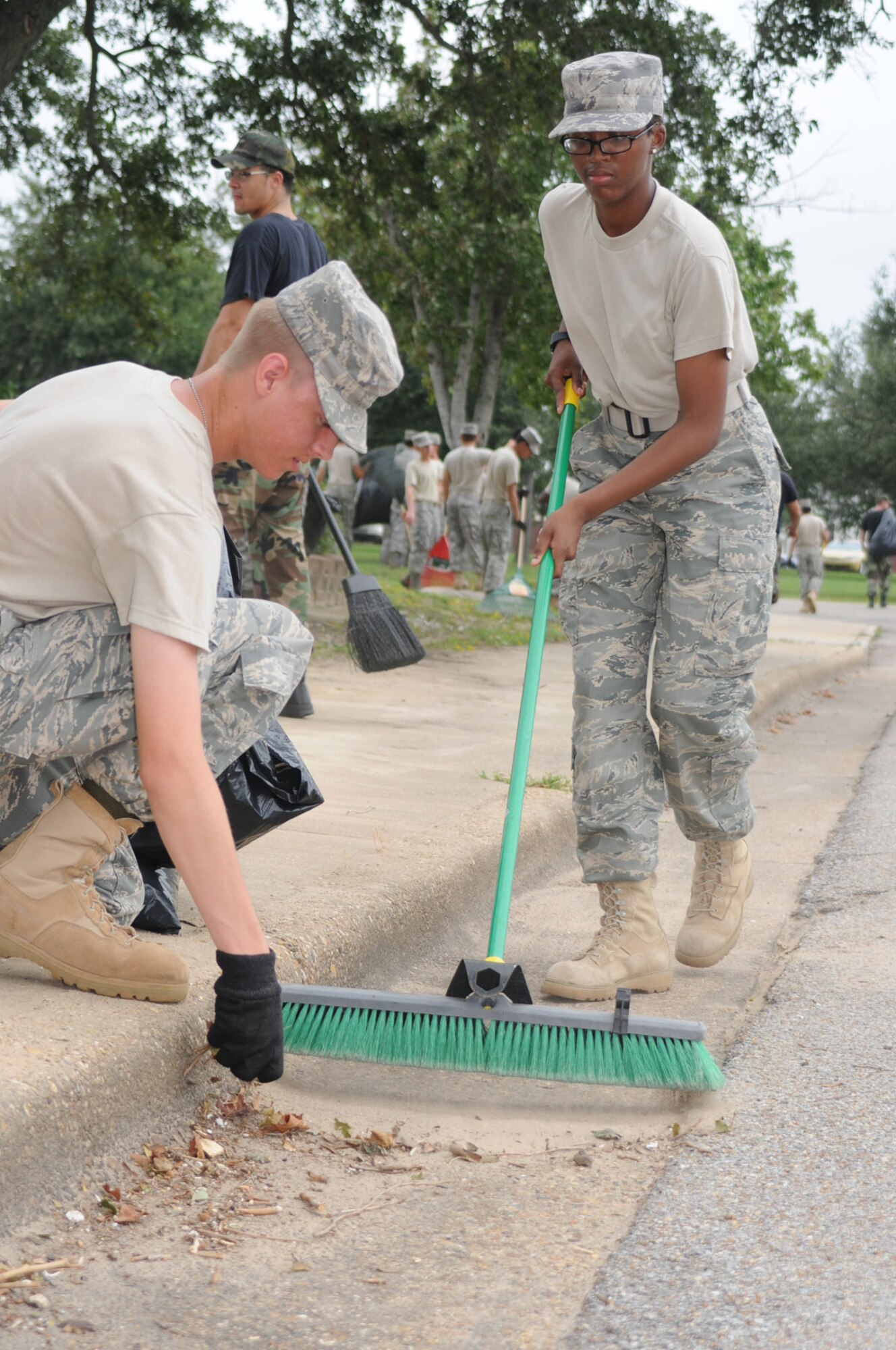 Airmen Basic Jacob Thomas, left, and Cheetarah Lee clean up debris from Hurricane Gustav on the base Sept. 2 near the 81st Civil Engineer Squadron complex. They’re students from the 338th Training Squadron.  More than 500 students donned gloves and hauled trash bags to help clean up after the Category 2 storm.  (U.S. Air Force photo by Kemberly Groue)
