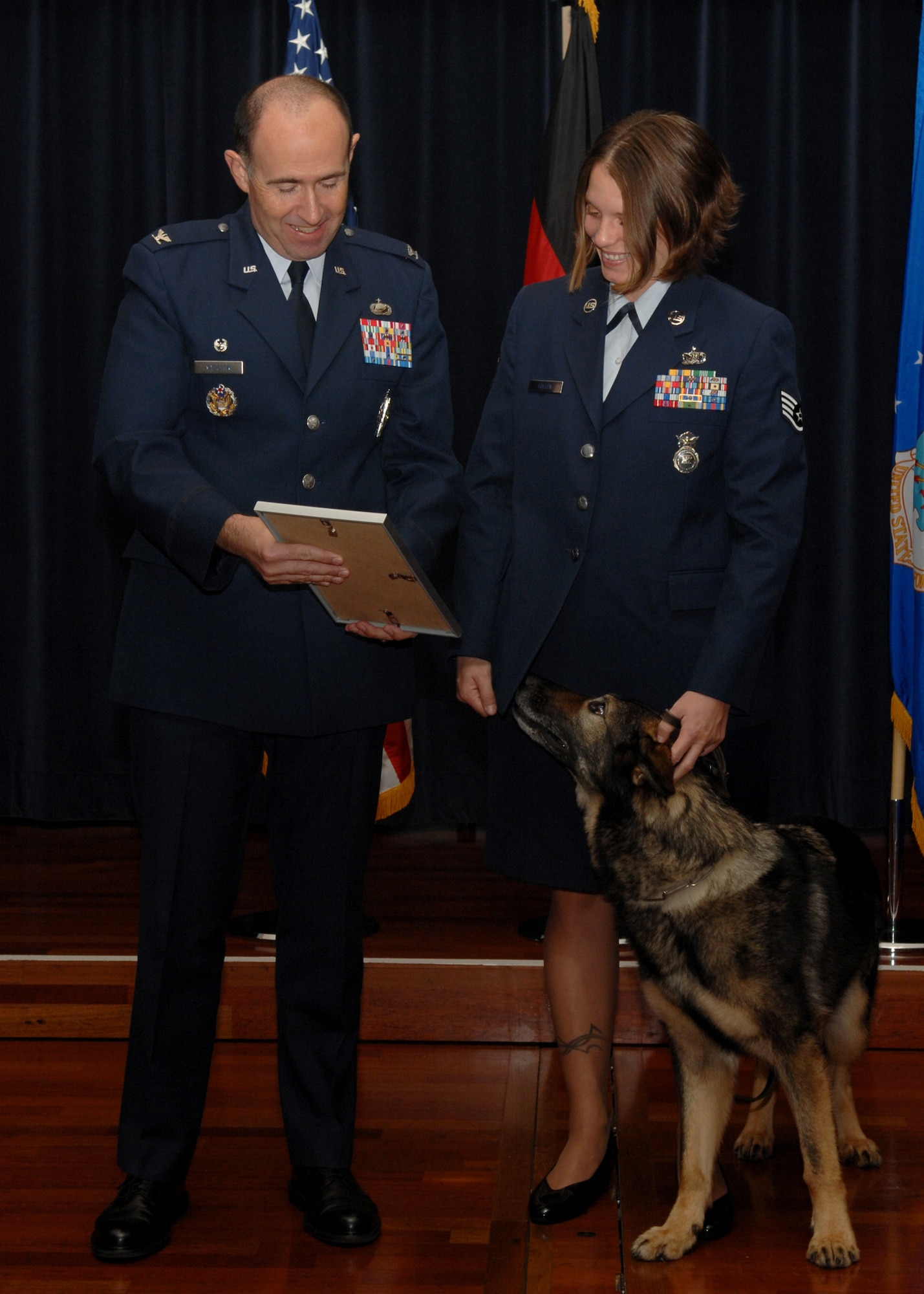 SPANGDAHLEM AIR BASE, Germany -- Staff Sgt. Patricia Fuller, 52nd Security Forces Squadron, and retired Military Working Dog Agar, look at MWD Agar’s retirement orders Sept. 4, 2008. Over the last five years, MWD Agar served his handlers and the U.S. Air Force with loyalty and honor. He was retired from service and adopted by Sergeant Fuller, his handler of two and a half years. (U.S. Air Force photo by Airman Staci Miller)