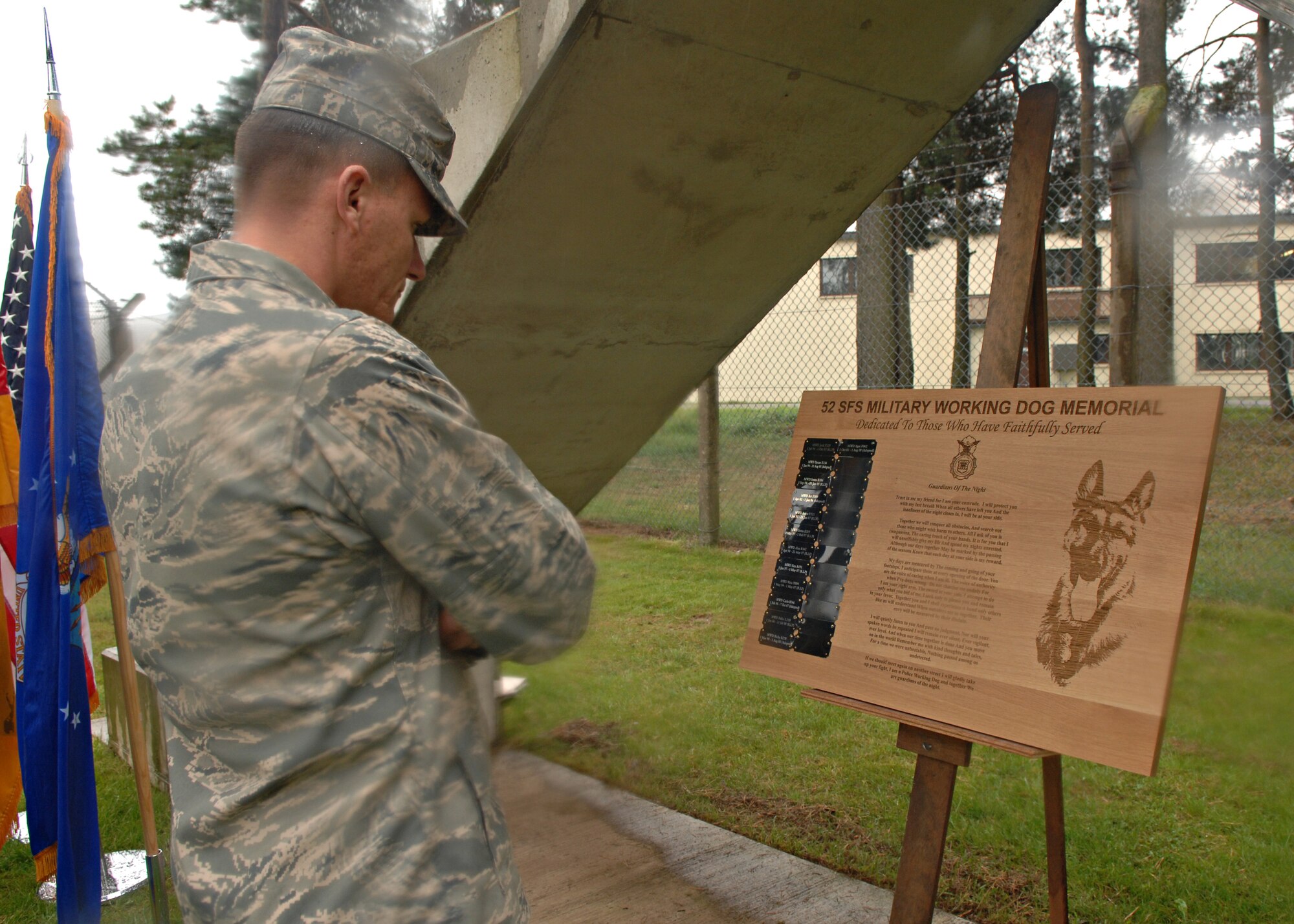 SPANGDAHLEM AIR BASE, Germany -- Maj. Lance French, 52nd Contracting Squadron commander, withstood the pouring rain to observe the new Military Working Dog memorial plaque, during an MWD Memorial Sept. 3, 2008. The memorial plaque honored 11 MWDs, five of which completed their military service and were adopted by their handlers. The other seven MWDs died while on active duty of natural causes. (U.S. Air Force photo by Airman Staci Miller)