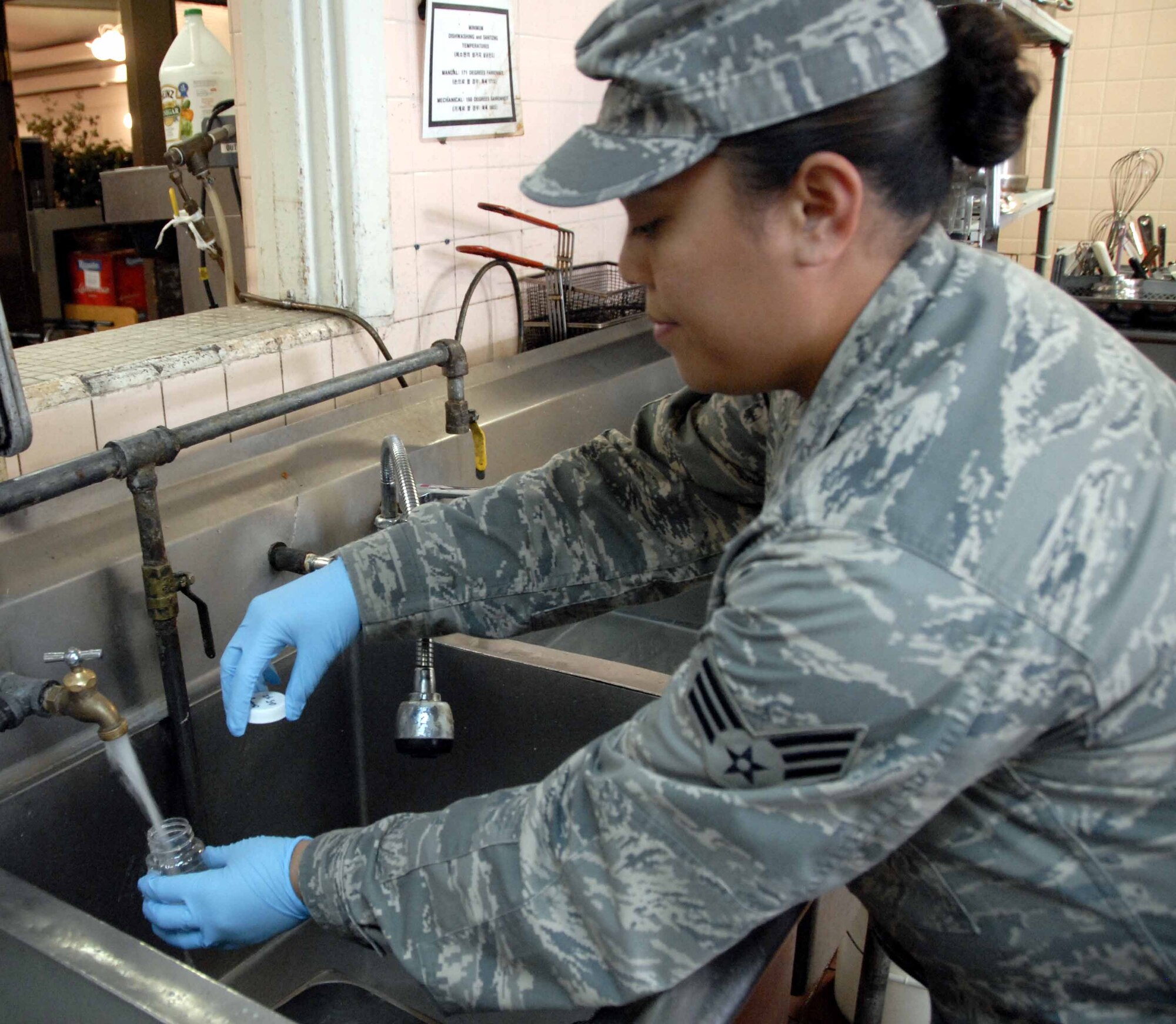 OSAN AIR BASE, Republic of Korea -- Senior Airman Verna Munoz, 51st Aerospace Medicine Squadron Bioenvironmental Engineering technician, gathers a sample of tap water during a routine health and safety check at the Challenger Club. The 51st AMDS’s Bioenvironmental Engineering Flight routinely tests Osan’s water supply to ensure water is safe to consume. (U.S. Air Force photo/Staff Sgt. Candy Knight)