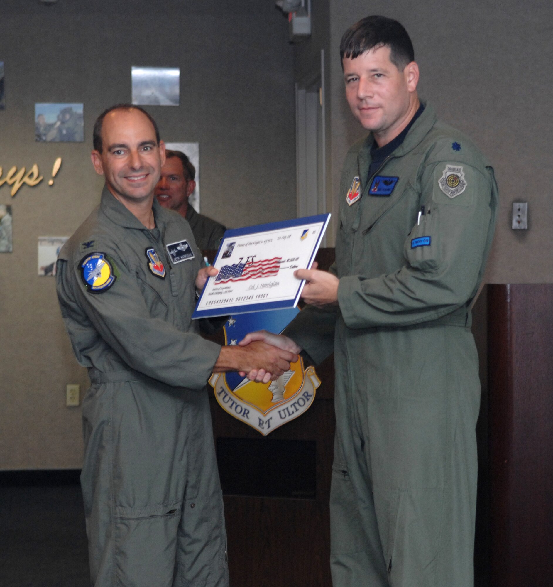 Lt. Col. Mike Hernandez receives a check on behalf of the 7th Fighter Squadron from Col. Jeff Harrigian, 49th Fighter Wing commander, at the 49 FW Headquarters building at Holloman Air Force Base, N.M., Sept. 10. The 7 FS received a check for $1,500 to use for quality of life initiatives within the squadron for placing 1st of the small squadrons in the Battle of Squadrons. (U.S. Air Force photo/Airman Sondra Escutia)