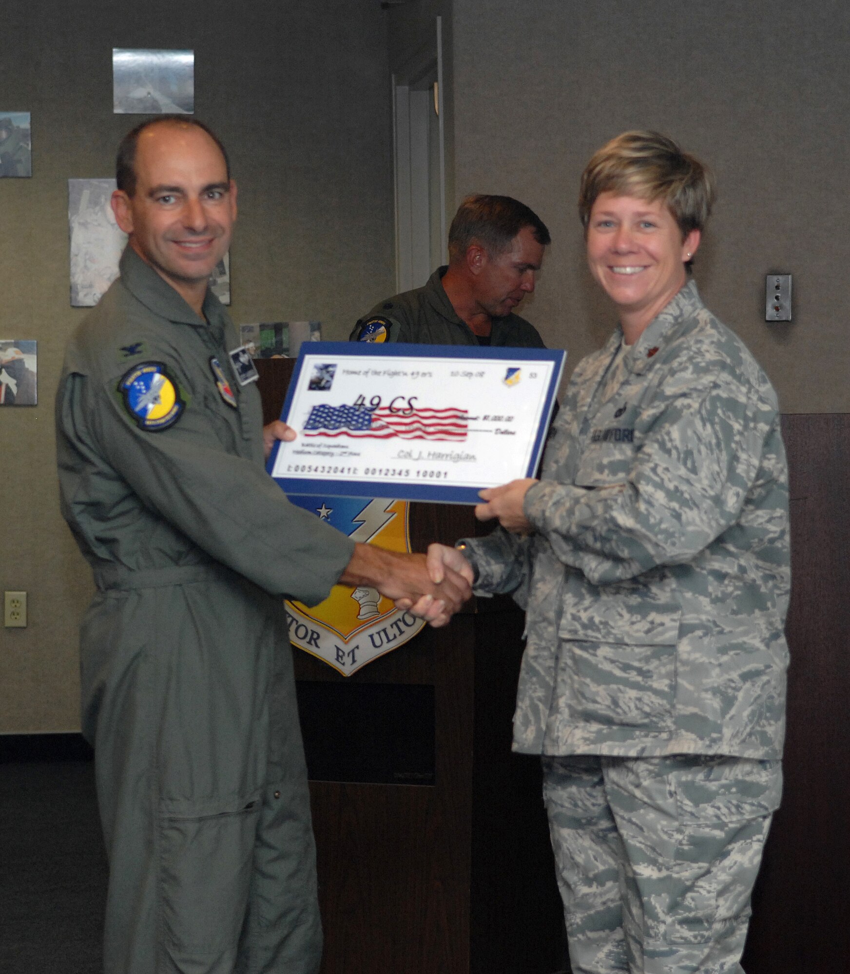 Maj. Marlyce Roth receives a check on behalf of the 49th Communications Squadron from Col. Jeff Harrigian, 49th Fighter Wing commander, at the 49 FW Headquarters building at Holloman Air Force Base, N.M., Sept. 10. The 49 CS received a check for $1,500 to use for quality of life initiatives within the squadron for placing 2nd of the medium squadrons in the Battle of Squadrons. (U.S. Air Force photo/Airman Sondra Escutia)