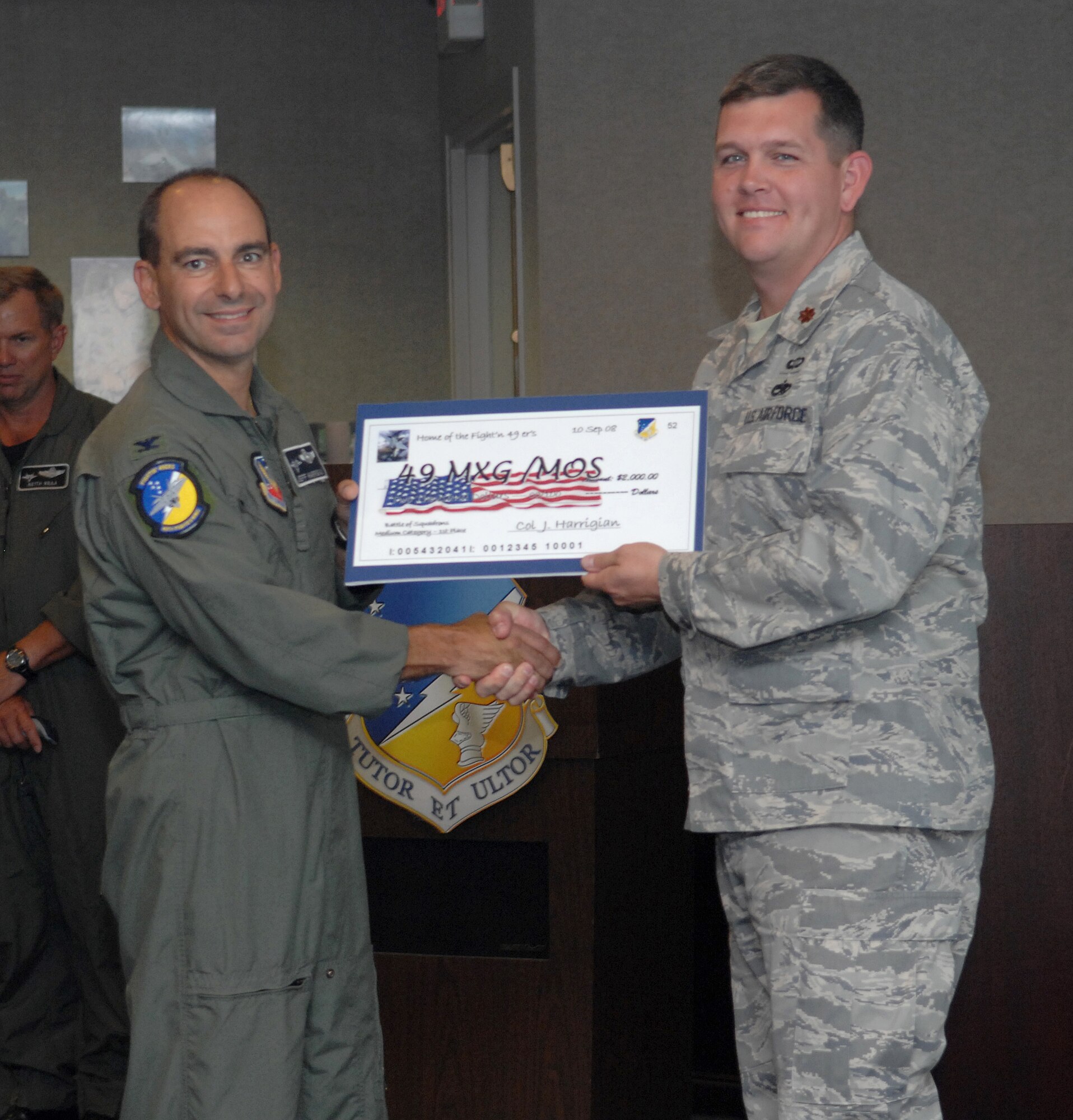 Maj. Anthony Babcock receives a check on behalf of the 49th Maintenance Operations Squadron from Col. Jeff Harrigian, 49th Fighter Wing commander, at the 49 FW Headquarters building at Holloman Air Force Base, N.M., Sept. 10. The 49 MOS received a check for $2,500 to use for quality of life initiatives within the squadron for placing 1st of the medium squadrons in the Battle of Squadrons. (U.S. Air Force photo/Airman Sondra Escutia)