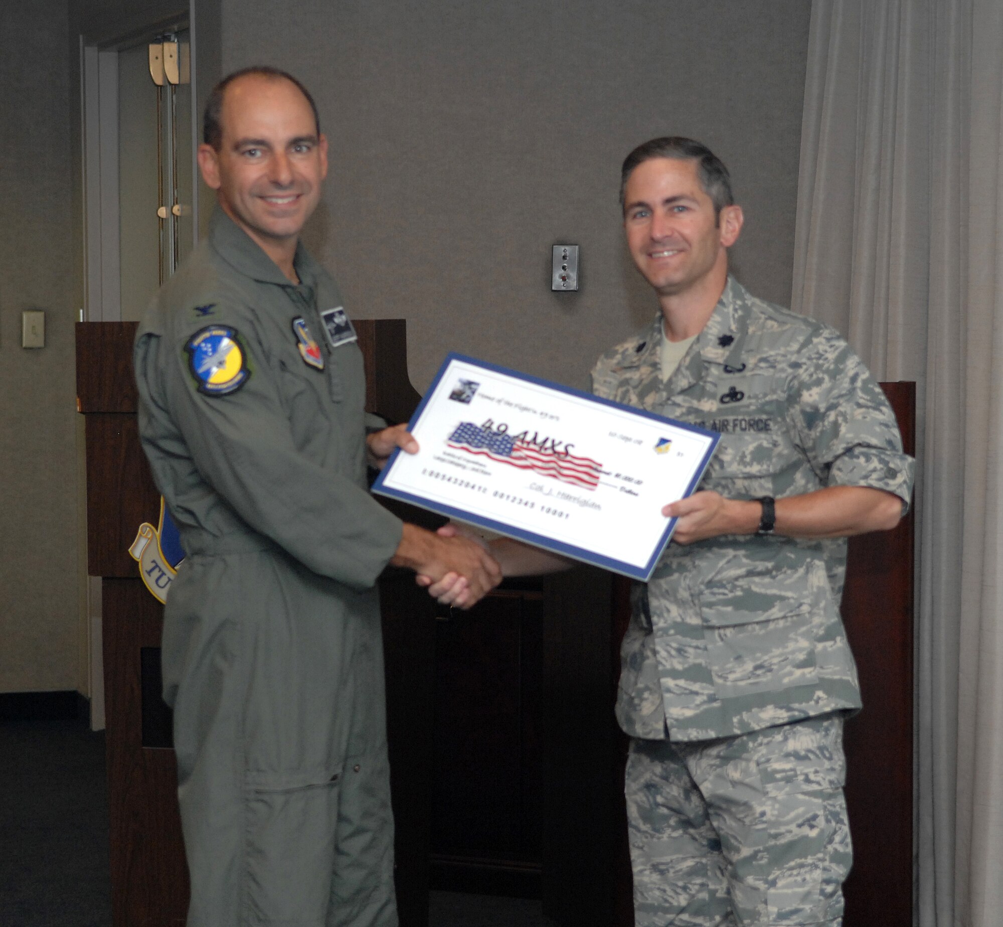 Lt. Col. Steven James receives a check on behalf of the 49th Aircraft Maintenance Squadron from Col. Jeff Harrigian, 49th Fighter Wing commander, at the 49 FW Headquarters building at Holloman Air Force Base, N.M., Sept. 10. The 49 AMXS received a check for $1,000 to use for quality of life initiatives within the squadron for placing 3rd of the large squadrons in the Battle of Squadrons. (U.S. Air Force photo/Airman Sondra Escutia)