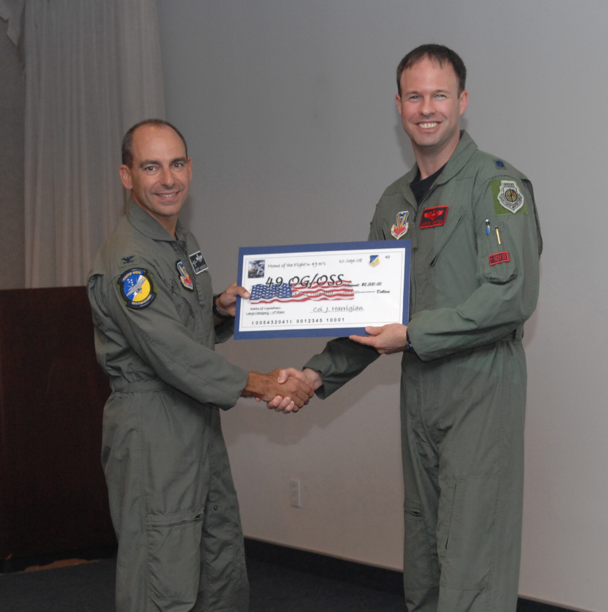 Lt. Col. Harvey Newton receives a check on behalf of the 49th Operations Support Squadron from Col. Jeff Harrigian, 49th Fighter Wing commander, at the 49 FW Headquarters building at Holloman Air Force Base, N.M., Sept. 10. The 49 OSS received a check for $2,500 to use for quality of life initiatives within the squadron for placing 1st of the large squadrons in the Battle of Squadrons. (U.S. Air Force photo/Airman Sondra Escutia)