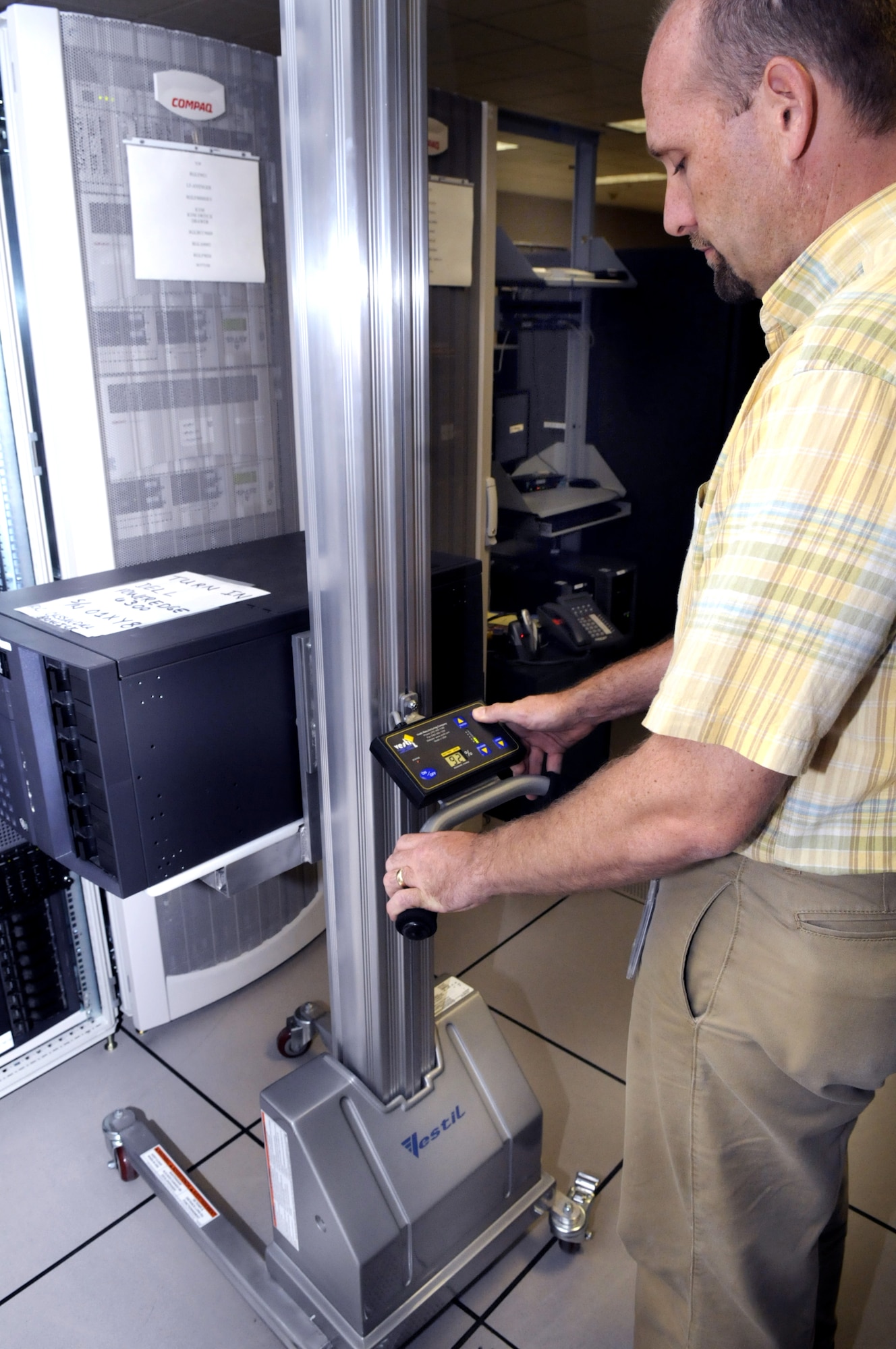 Luke Sarazine uses a powered lift to move a computer server into a shelving unit. One person can move a server with the lift where it took 3 people before to do it manually. U. S. Air Force photo by Sue Sapp