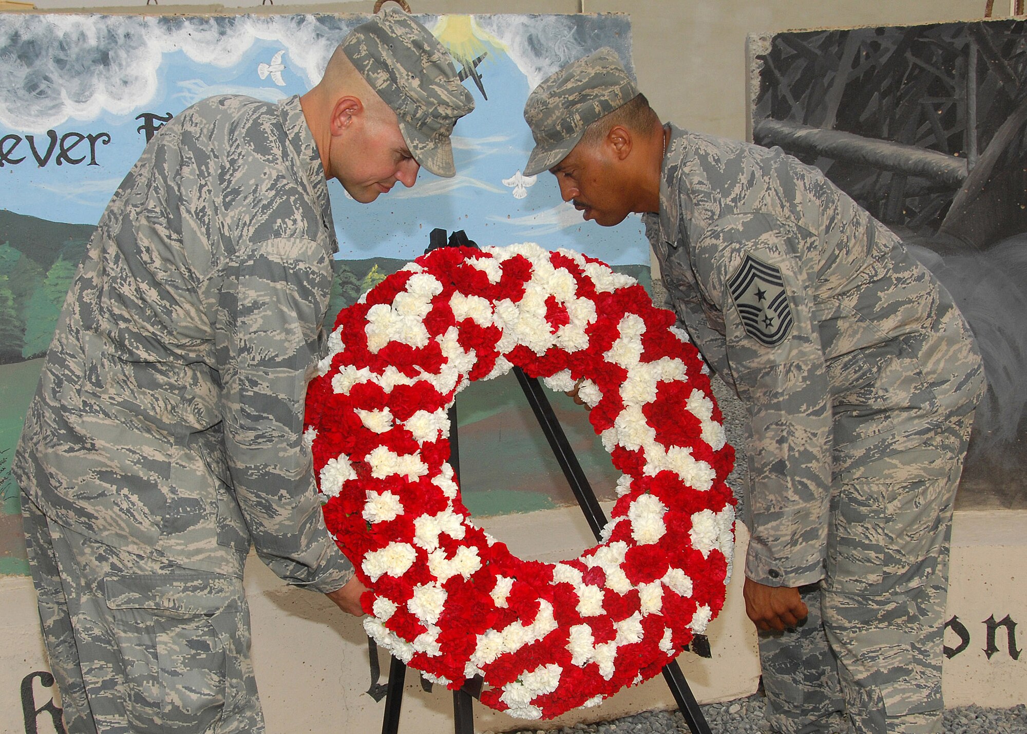 Col. Cameron Torrens and Chief Master Sgt. Jeffrey Antwine place a wreath at the Sept. 11 memorial during the remembrance ceremony Sept. 11 at an air base in Southwest Asia. The ceremony included a wreath-laying ceremony, a 21-gun salute and the playing of "Taps" to honor the memory of those that perished and survived the terrorist attacks of Sept. 11, 2001. Colonel Torrens is the 386th Air Expeditionary Wing commander, and Chief Antwine is the 386th AEW command chief. (U.S. Air Force photo/Tech. Sgt. Raheem Moore) 
