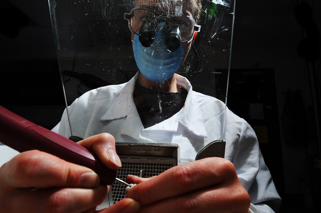 Staff Sgt. Amy Cadavero looks through magnifying goggles as she shapes a porcelain crown using a dental drill with a diamond bur drill bit Sept. 9 at Eielson Air Force Base, Alaska. Once Sergeant Cadavero receives the impressions made from a patient's teeth, she will then make it into a cast mold to start shaping the crown so it will fit comfortably in a patient's mouth. This process can take up to a week to finish. She is a dental lab technician assigned to the 354th Medical Operations Squadron (U.S. Air Force photo/Airman 1st Class Jonathan Snyder) 