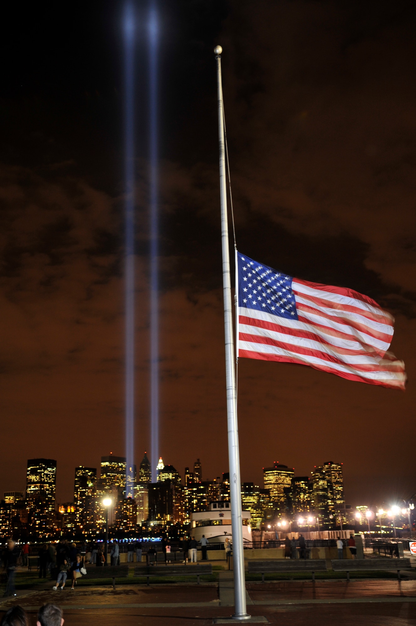 The American flag flies at half-staff over Liberty State Park, N.J., as twin beams of light illuminate the skies over New York City, N.Y., in the Tribute in Light Sept. 11, 2008. The Tribute in Light commemorated the seventh anniversary of the attack on the World Trade Center. (U.S. Air Force photo/Kenn Mann)