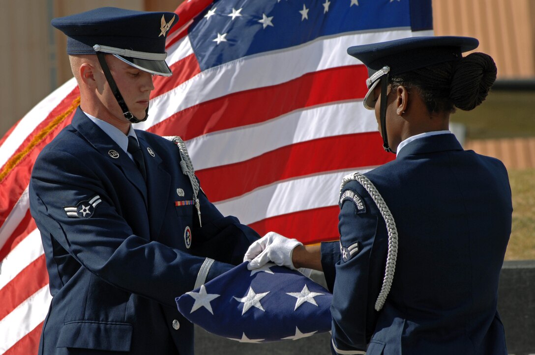 Airmen 1st Class Ray Wahl and Tashe Majors-Newsom, Ellsworth Honor Guard members, fold the American Flag during the 9/11 memorial at the South Dakota Air and Space Museum on Sept. 11. The honor guard performed a flag-folding ceremony at the museum in honor of those lost seven years ago. (U.S. Air Force photo by Airman Corey Hook)