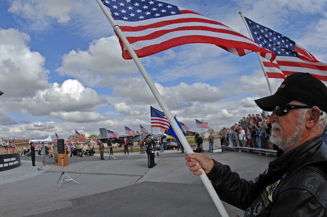 Curtis Eisemeraum, Patriot Guard rider, holds a flag at the South Dakota Air and Space Museum during the National Anthem at the 9/11 memorial on Sept. 11. The memorial ceremony was performed to honor those who lost their lives in the 9/11 tragedy and honor service members who have served and continue to serve since. (U.S. Air Force photo by Airman Corey Hook)