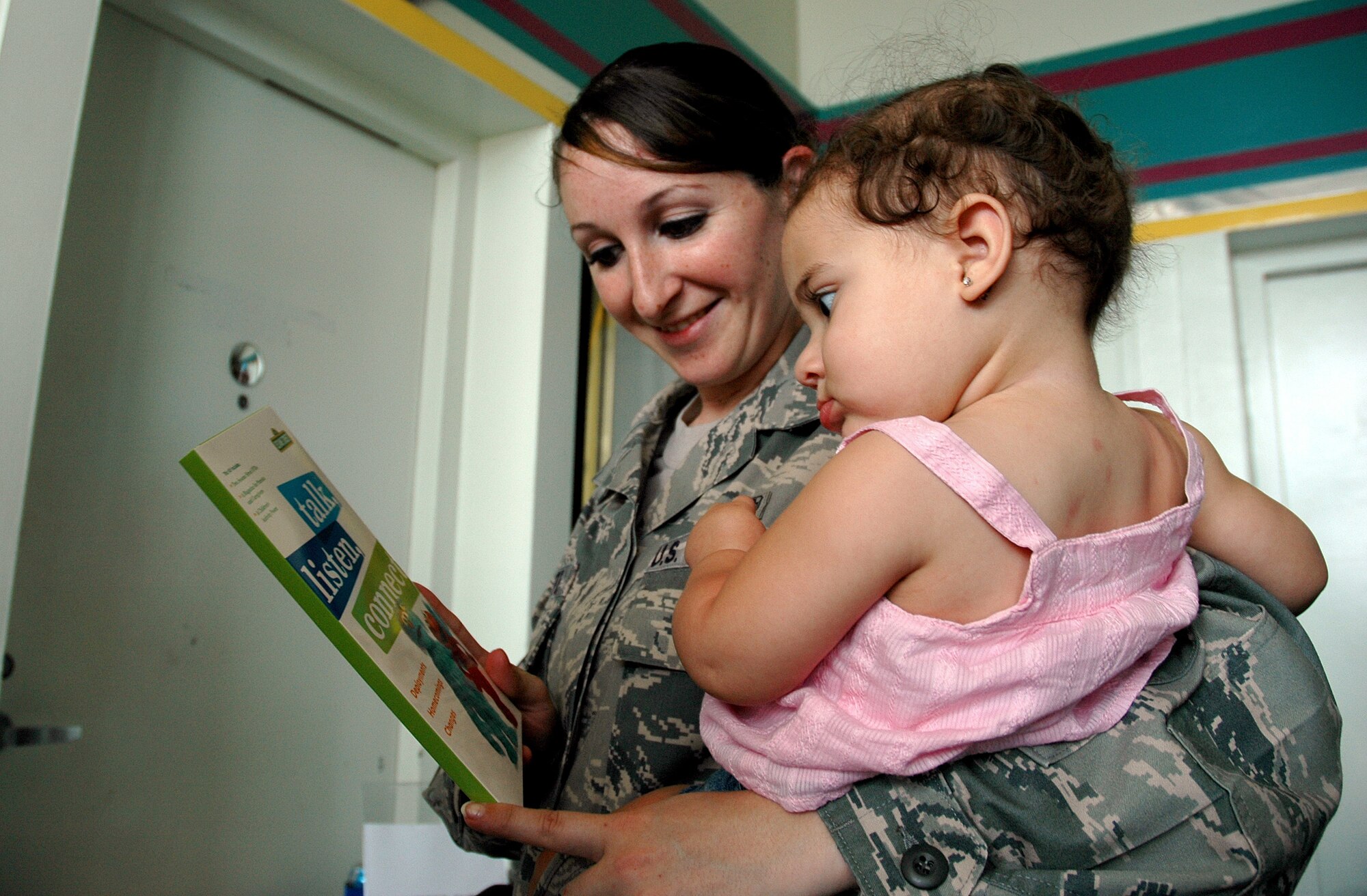 EGLIN AIR FORCE BASE, Fla. -- Senior Airman Rachael Marzette, 96th Aerospace Medical Squadron Public Health technician, shows a book to her 10-month-old daughter Amya at The Sesame Street Experience for Military Families performance at the base theater Sept 11. Sesame Workshop and the United Service Organizations partnered to bring the free 25-min show to more than 40 military installations across the United States as part of Sesame?s military outreach program Talk, Listen, Connect. (U.S. Air Force photo/Capt. Carrie L. Kessler)