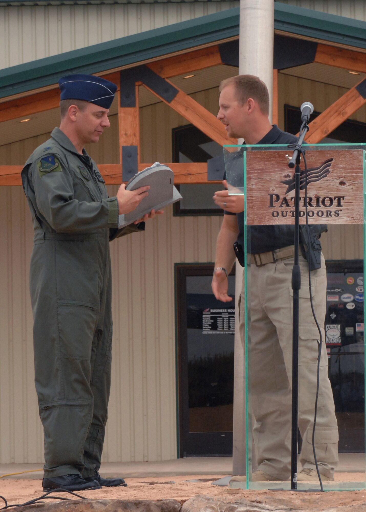 CANNON AIR FORCE BASE, N.M. - Mr. Stephen Powell, owner of Patriot Outdoors, presents Col. Hans Kaspar, 27th Special Operations vice wing commander, with a Sept. 11 memorial honoring servicemembers during a remembrance ceremony at Patriot Outdoors Sept. 11. The memorial honored all servicemembers serving during the Sept. 11, 2001 attacks. (U.S. Air Force photo/Airman 1st Class James R. Bell)